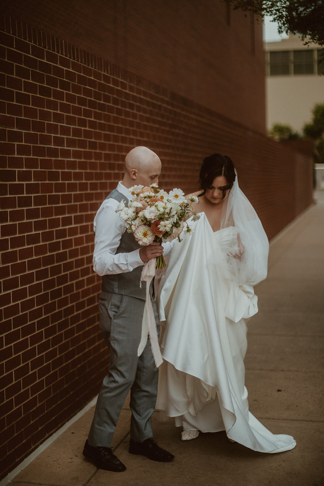 candid bride and groom fix dress