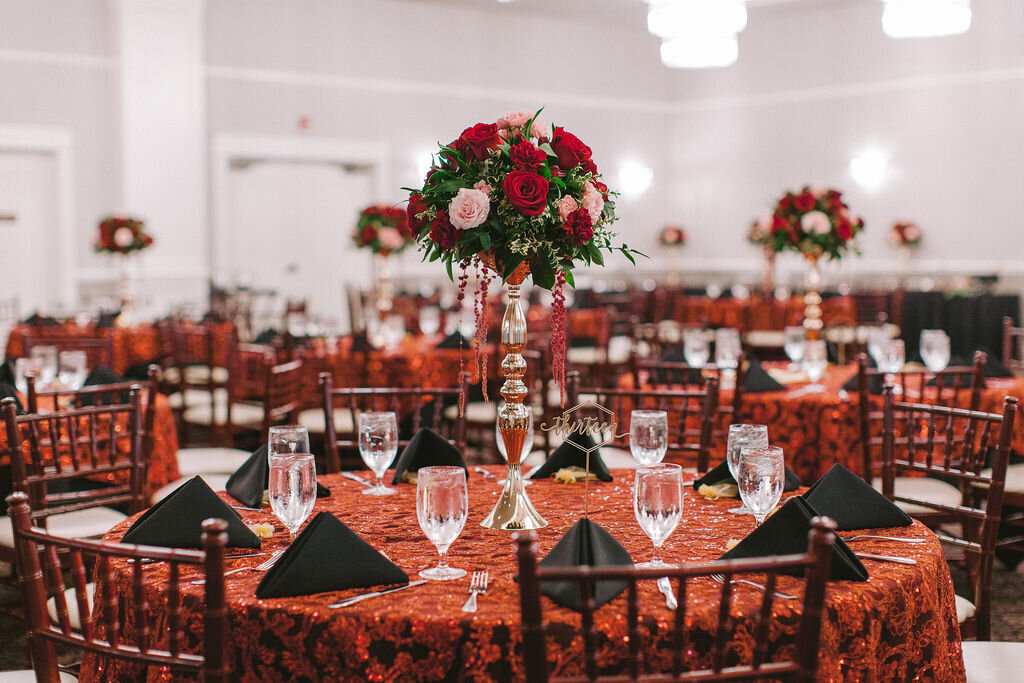 Burgundy linens with pink and gold centerpieces.