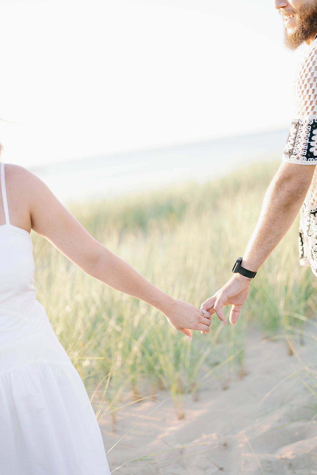 Detail photo of engaged couple holding hands at their Lake Michigan beach engagement session in New Buffalo
