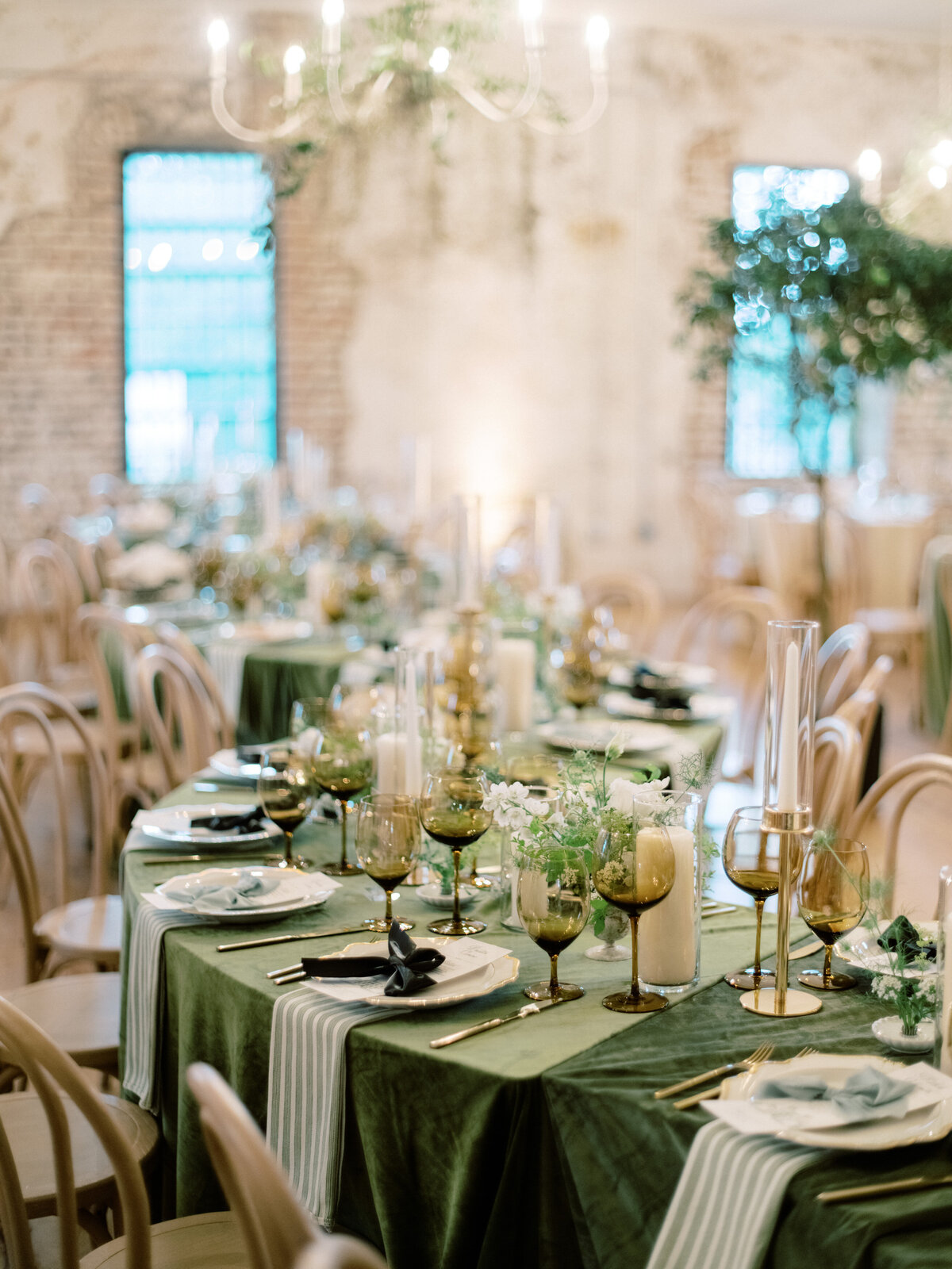 The image showcases an elegantly arranged dining table with green table linens, gold glassware, and subtle floral centerpieces, ideal for a sophisticated wedding.