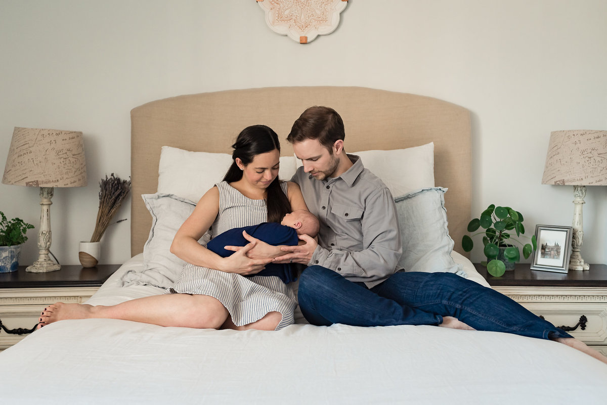 Mom and dad holding newborn baby girl on bed during Los Angeles Newborn Photography Session