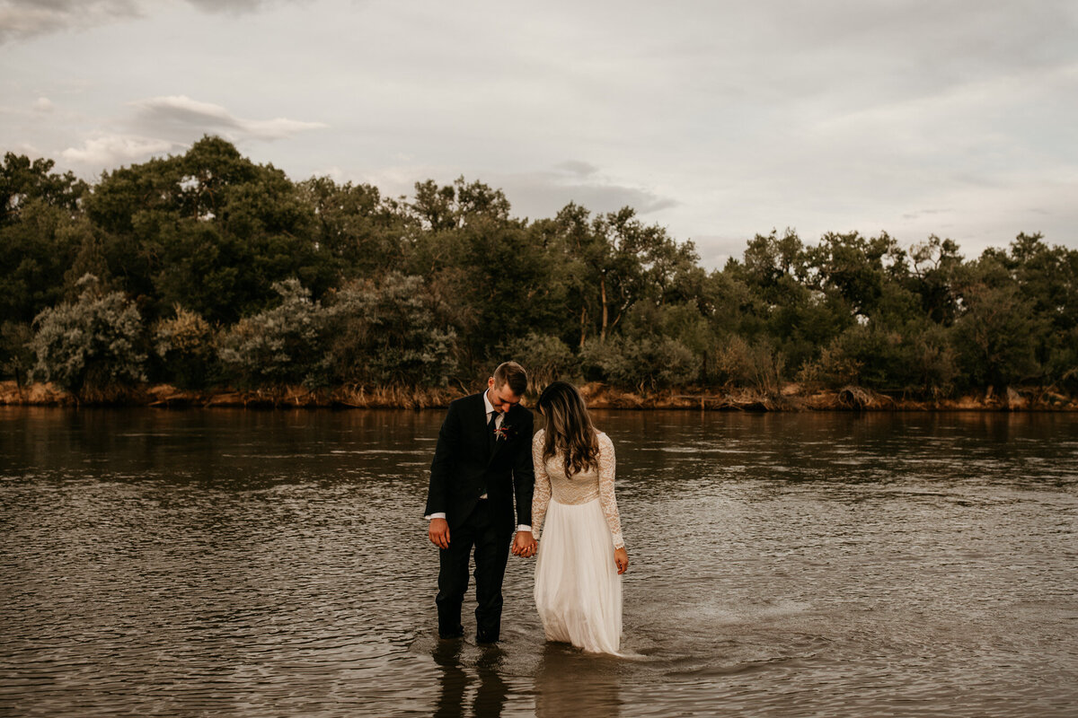 bride and groom walking through Albuquerque river