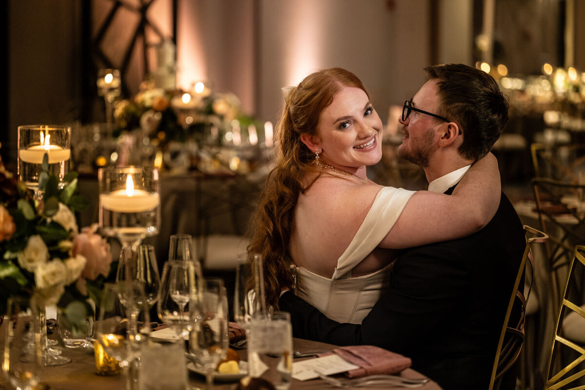A bride and groom are posing for a picture at their wedding reception