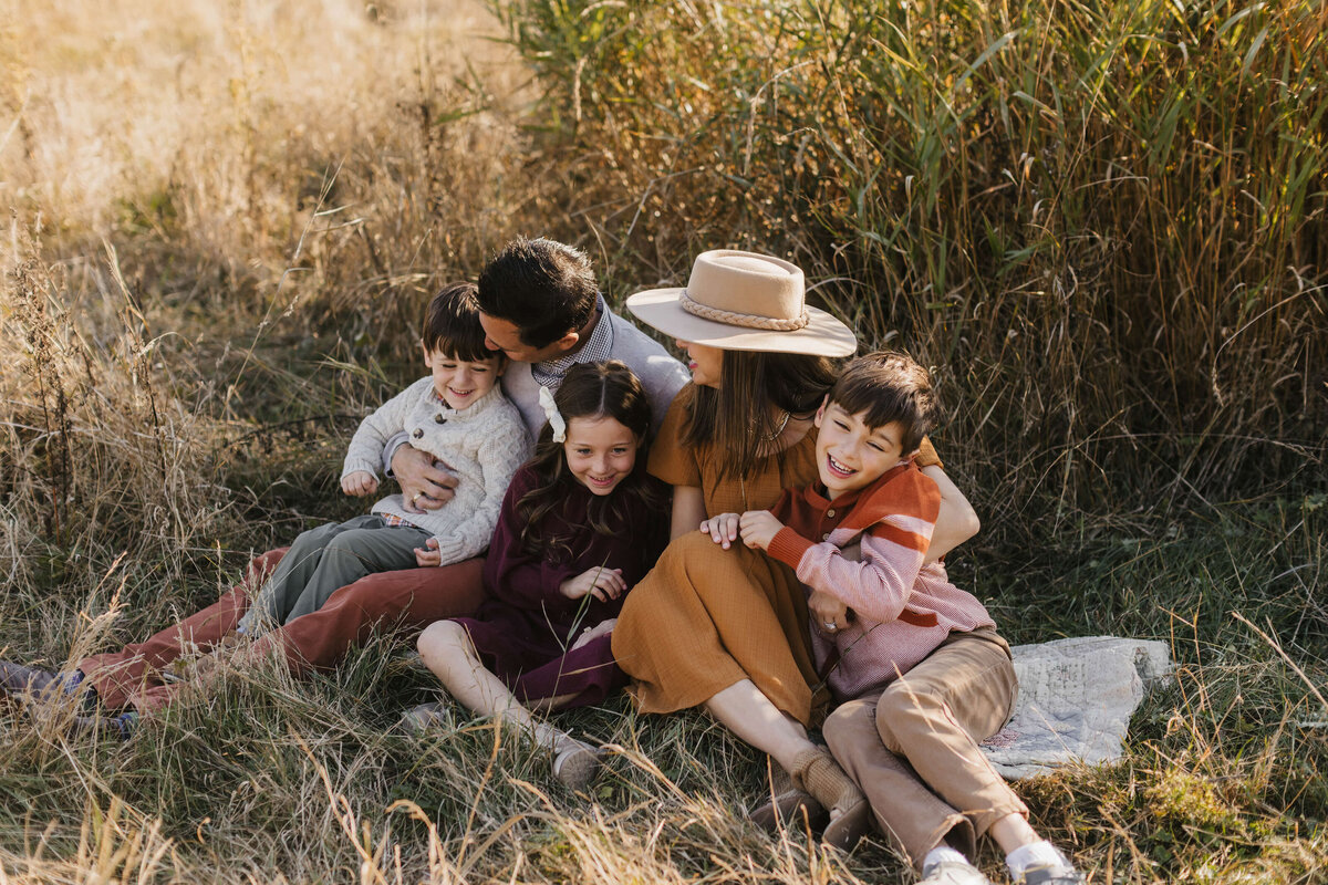 Snuggled up family on a blanket in the middle of a field in Seattle