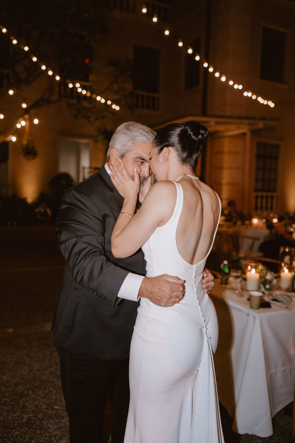 Bride holding her fathers face close during father daughter dance