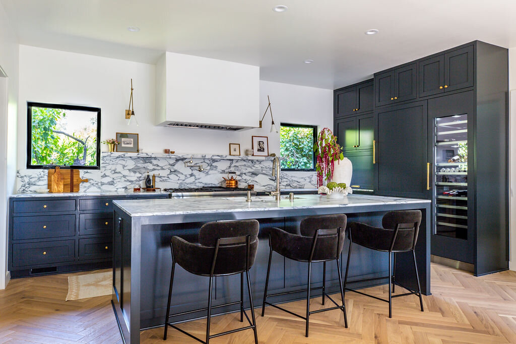 Kitchen with dark navy cabinets, herringbone floors, Corchia marble countertops and backsplash, and Thermador appliances
