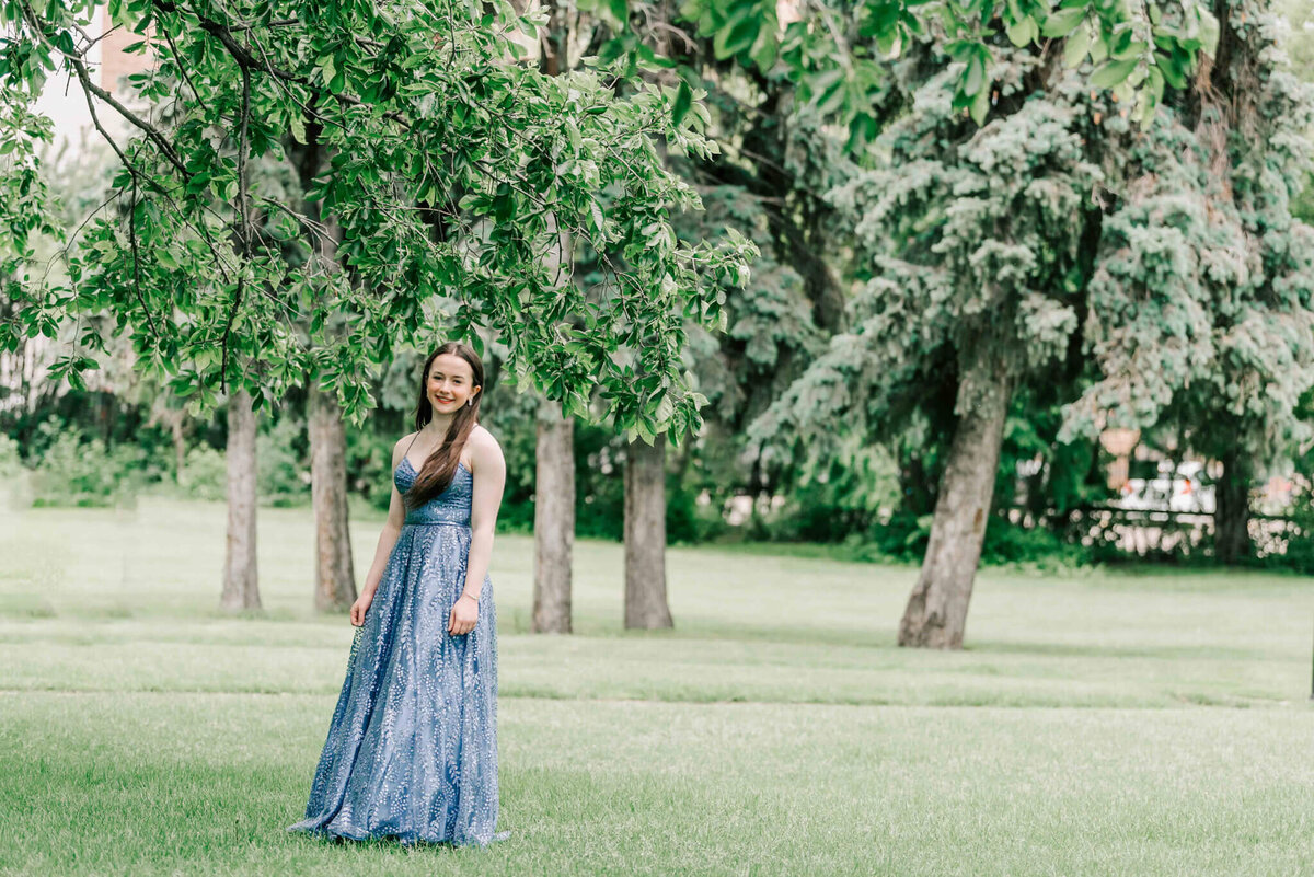 A girl standing under some trees. 