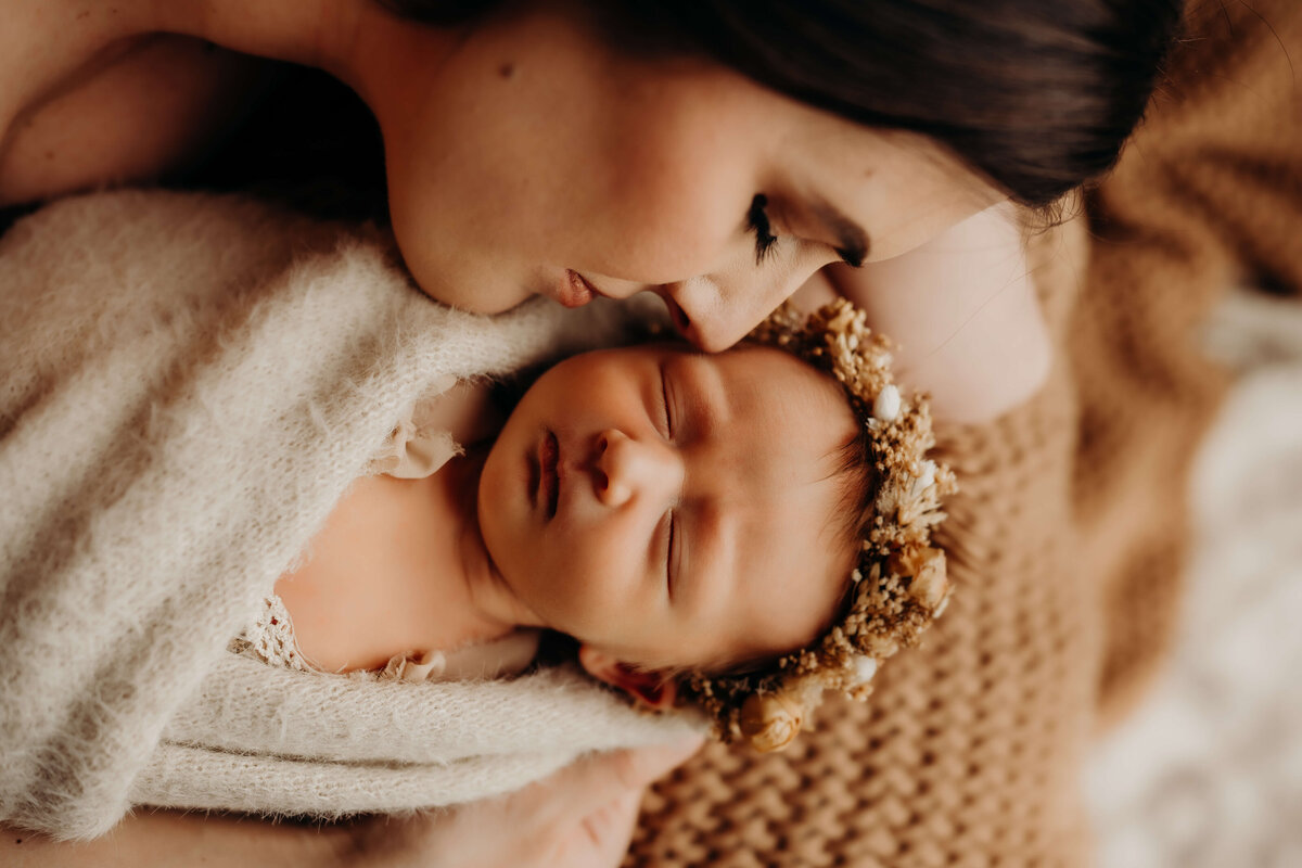 mother cuddles infant while baby furrows her brow