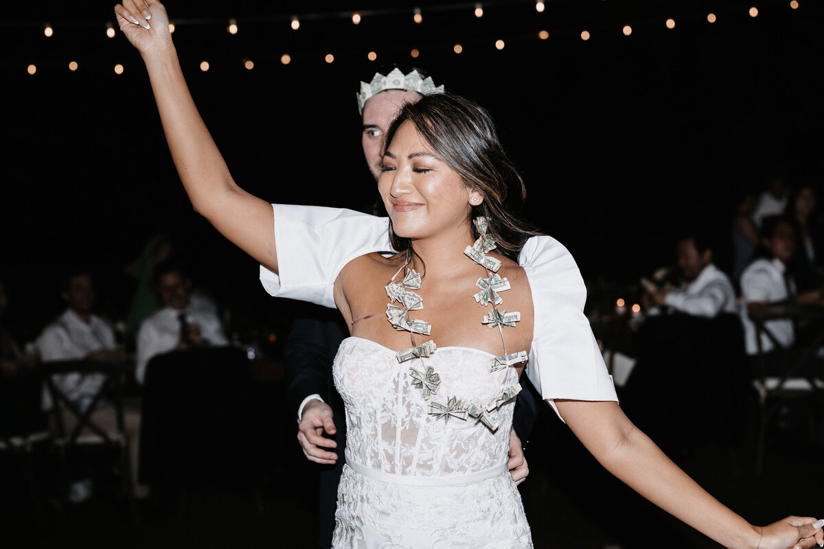 Bride wearing filipino sleeves and a necklace of money while groom reaches for her waist