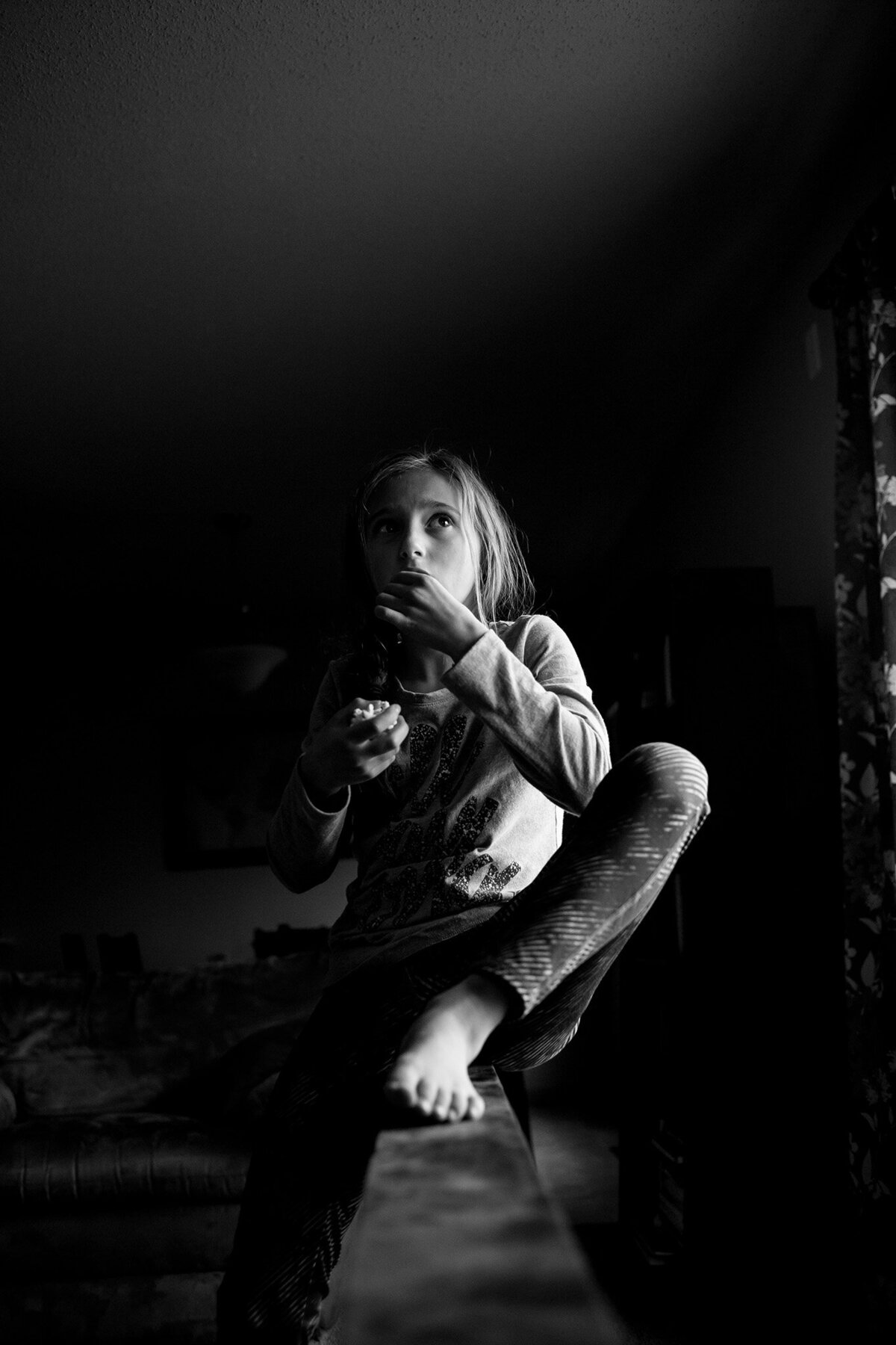 black and white photo of girl on balance beam eating snack