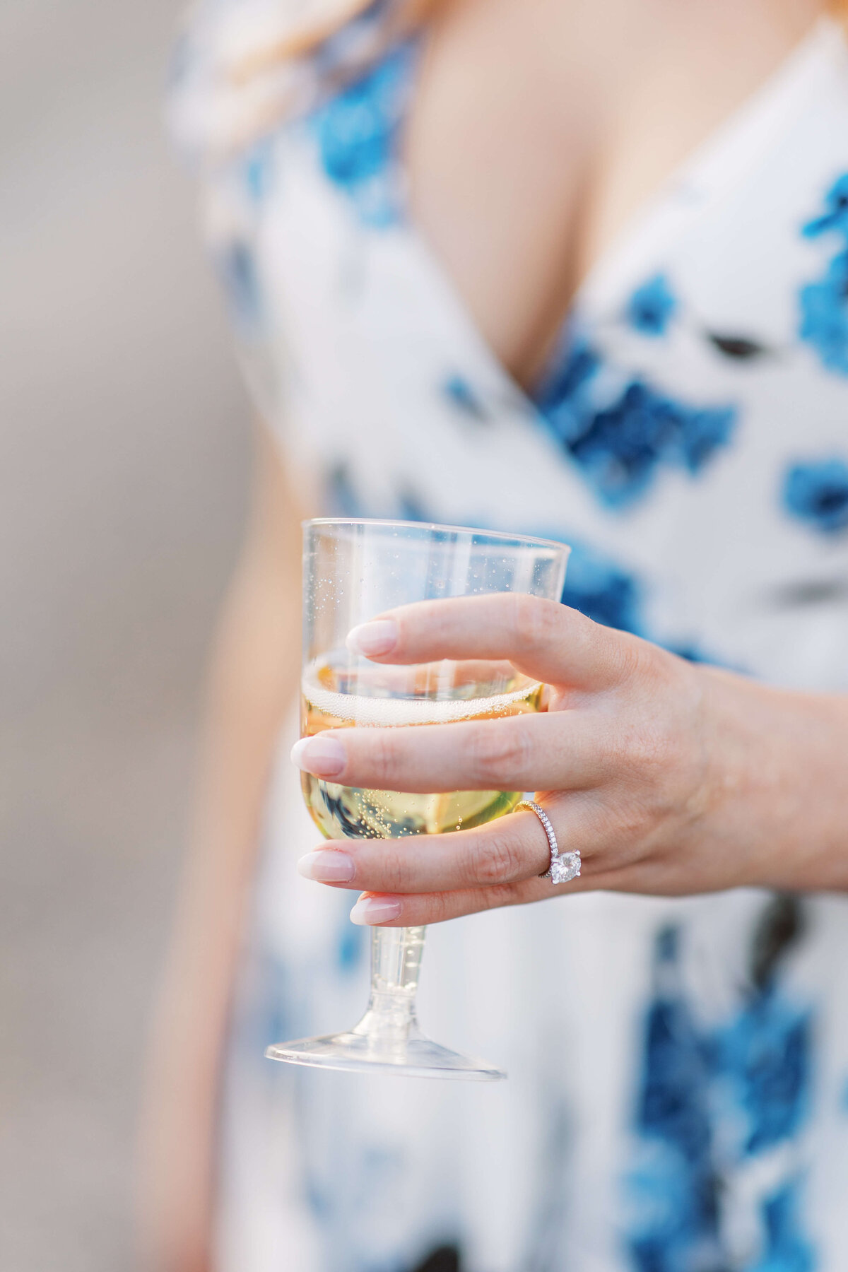 Bride to be displays her engagement ring as she holds a glass of champagne.