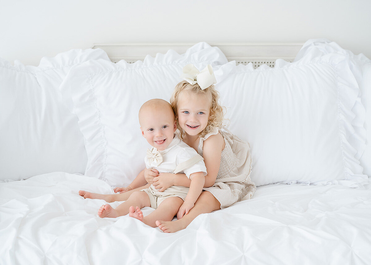 baby boy celebrating first birthday in a studio photoshoot in st simons island is photographed iwth his big sister