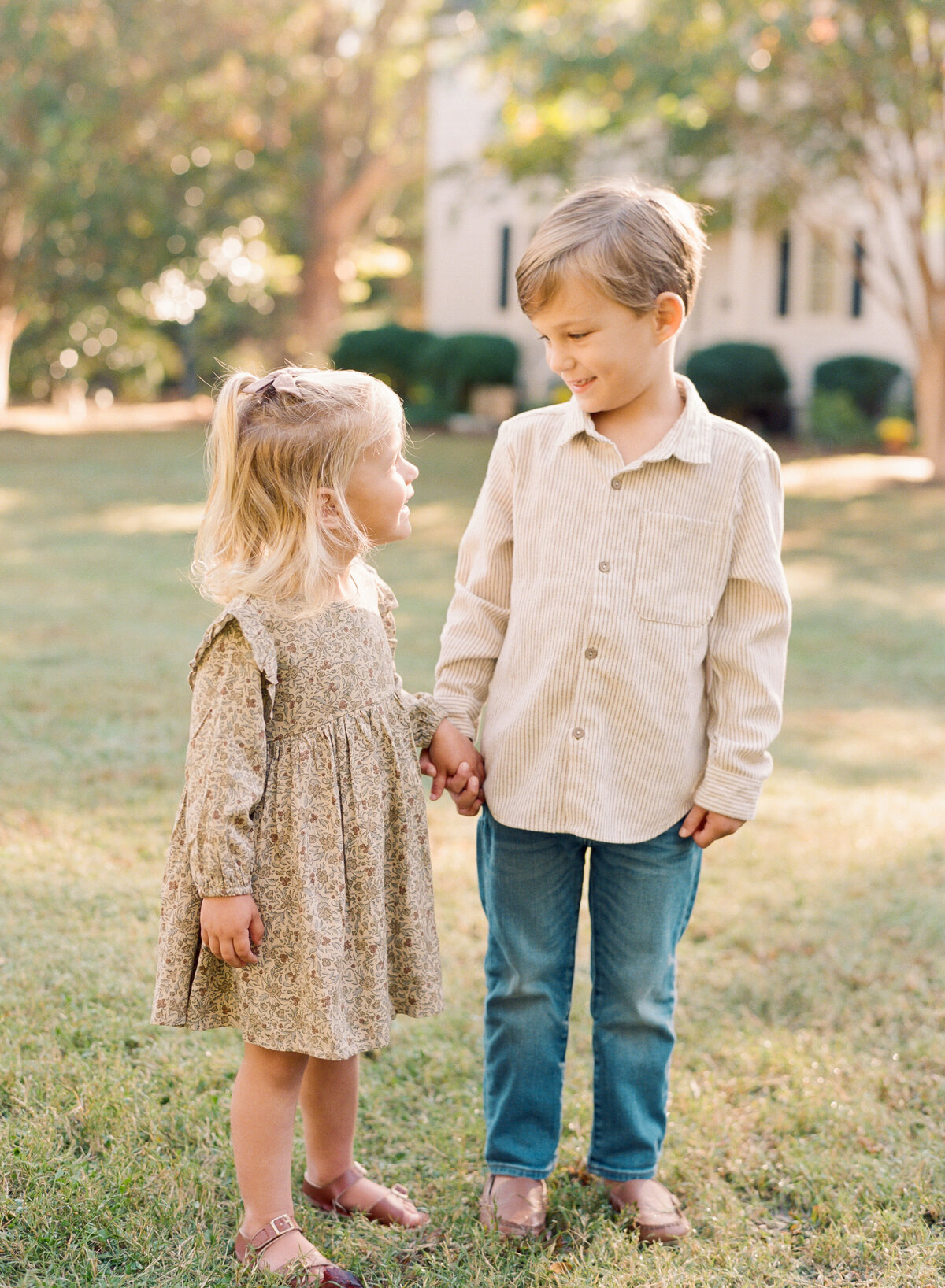 Siblings play during their fall family photos in Raleigh NC. Family walking during their family portrait session in Wake Forest, NC. Photographed by Raleigh family photographer A.J. Dunlap Photography.