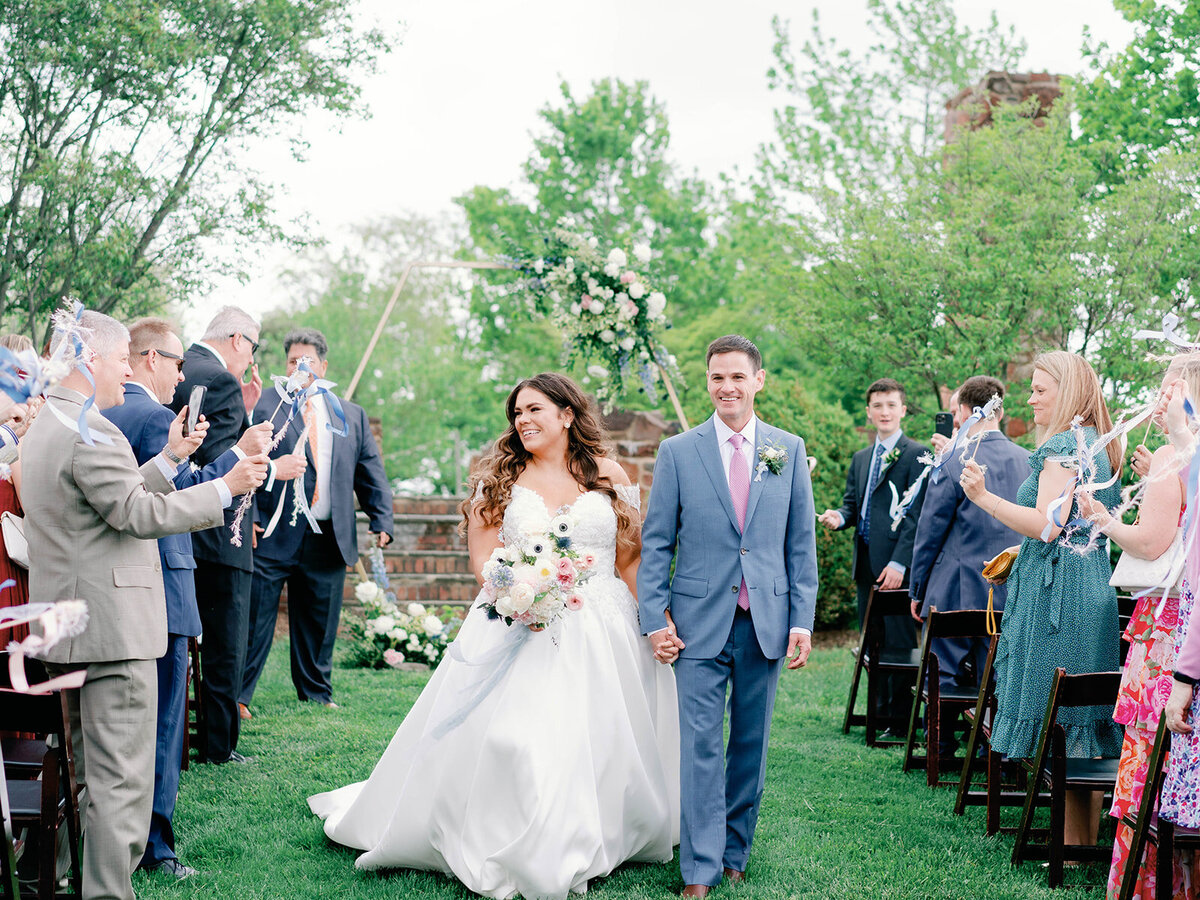 Bride and groom look at all their people as they are headed out of their wedding ceremony 
