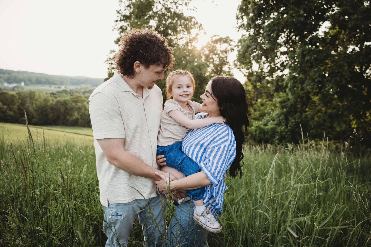 family standing in tall grass interacting in portrait session with reva davis photography