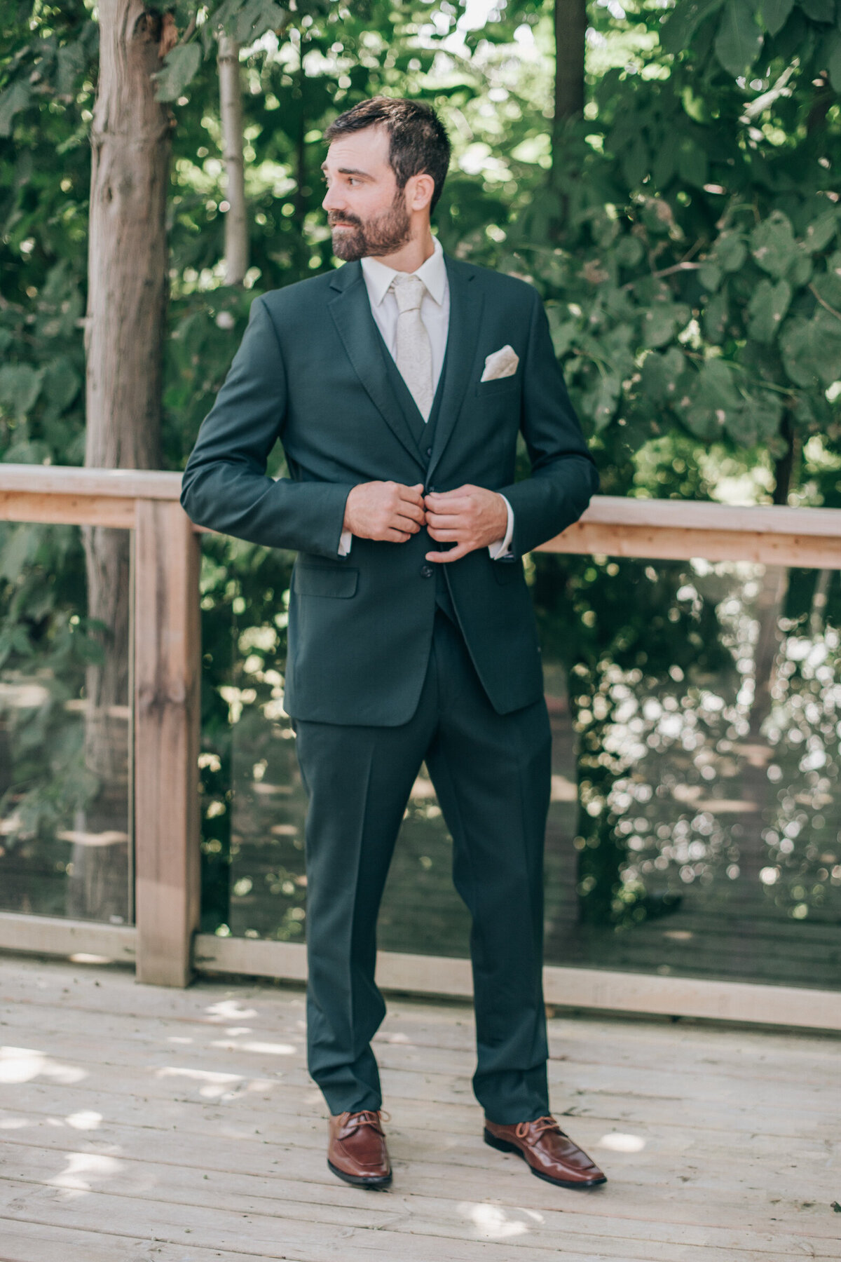 A groom in a green suit posing for photos