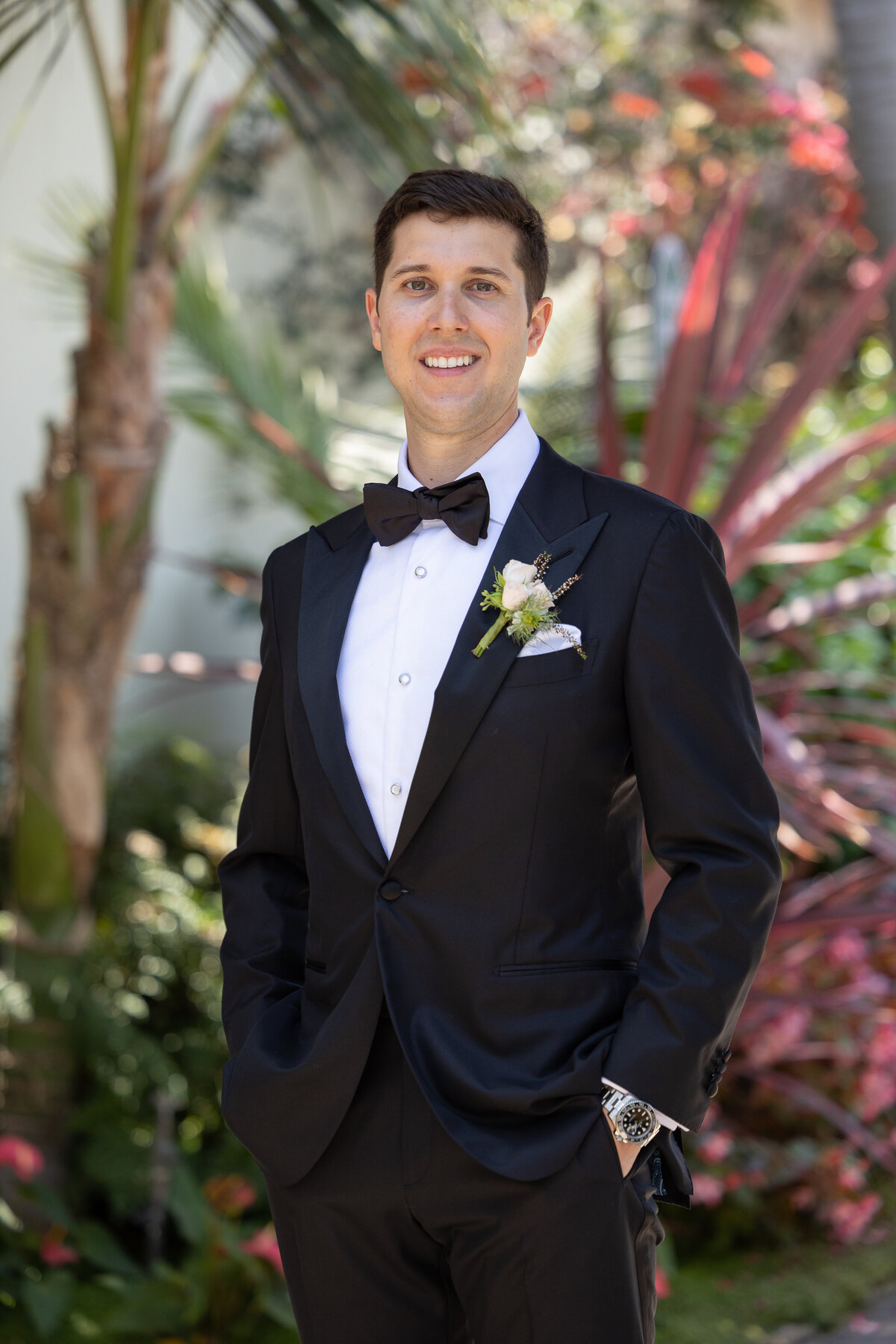 Groom wearing a black tuxedo with a black bow tie outside Bel Air Bay Club