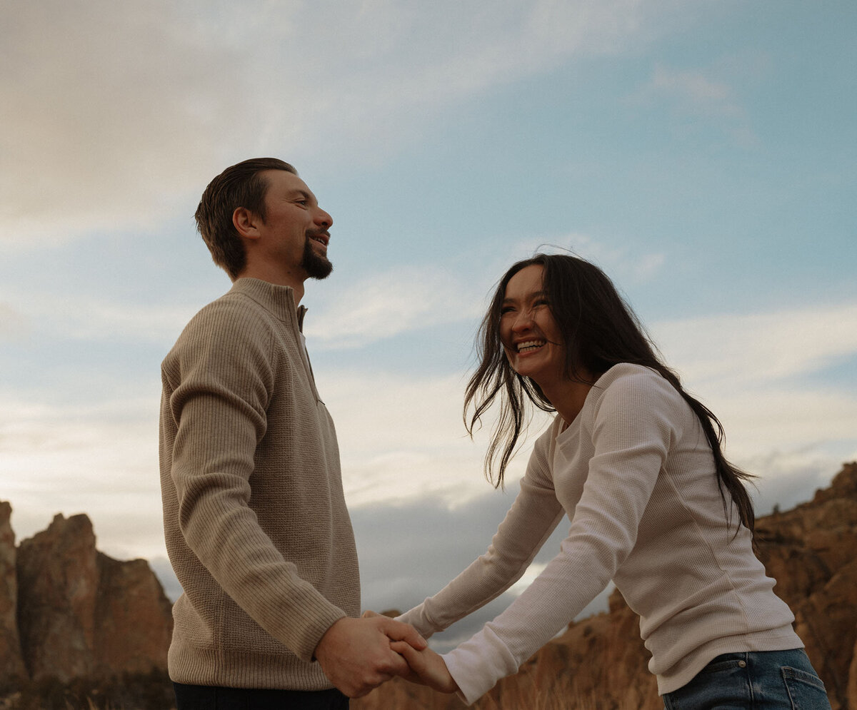 engaged couple holding hands and laughing during a candid moment in Bend, Oregon
