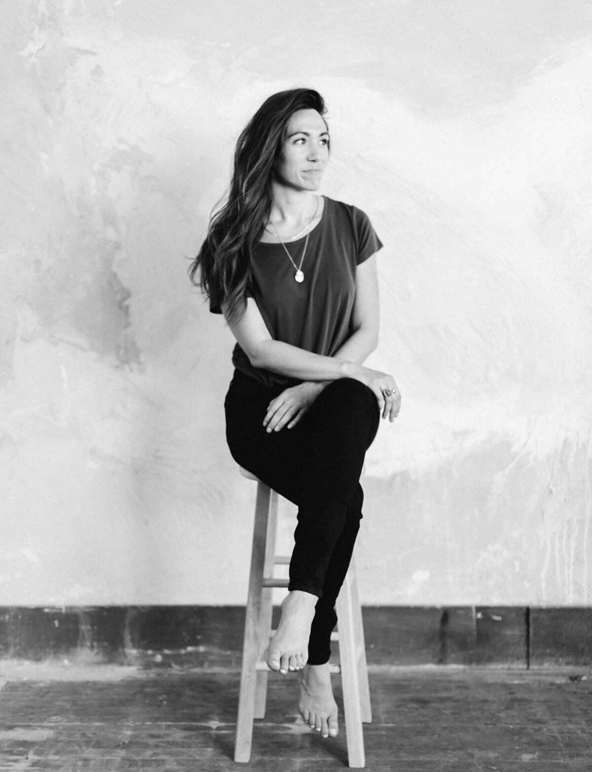 artist, calligrapher, stationer female business owner with painterly wall, sitting on stool, Detroit studio brand photography