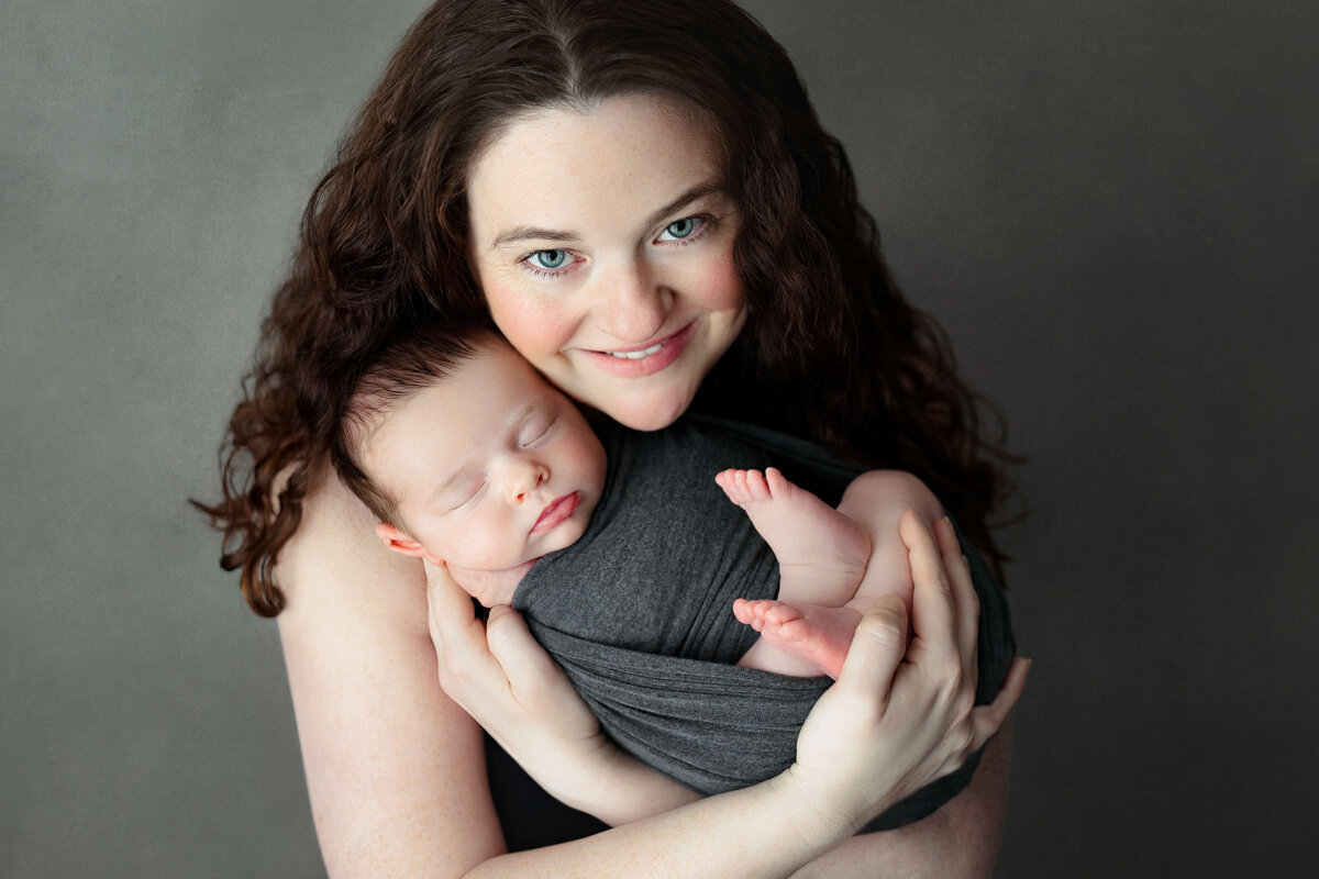 new mom holding her newborn baby   at a newborn photo session in northern va