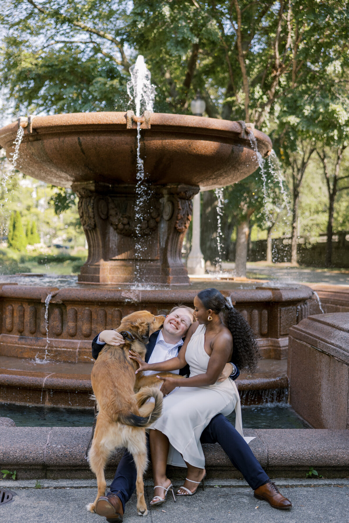 A couple shares a romantic moment in a formal garden along Michigan Avenue, surrounded by lush greenery and city charm.