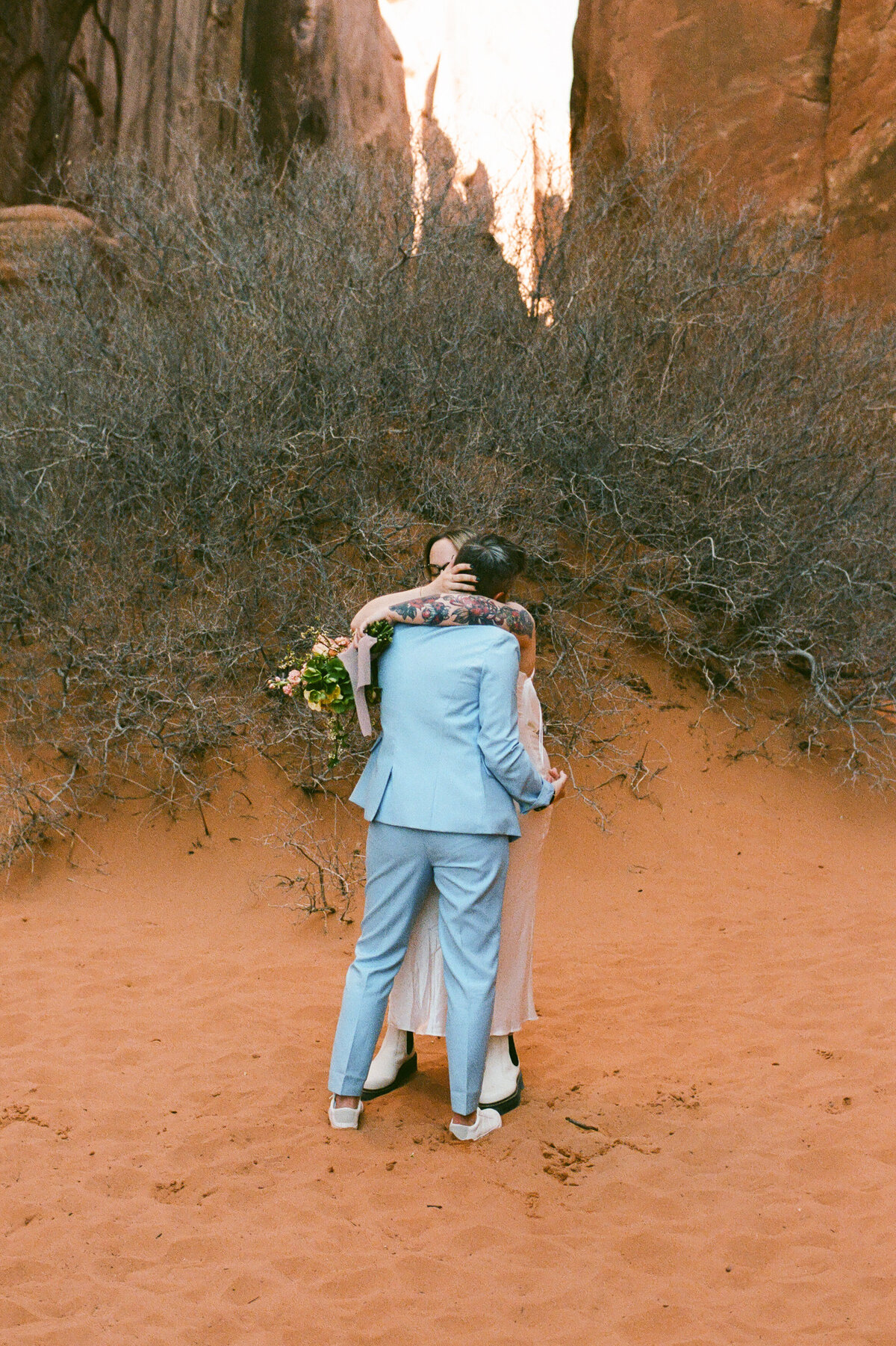 A couple hugs one another in the sand