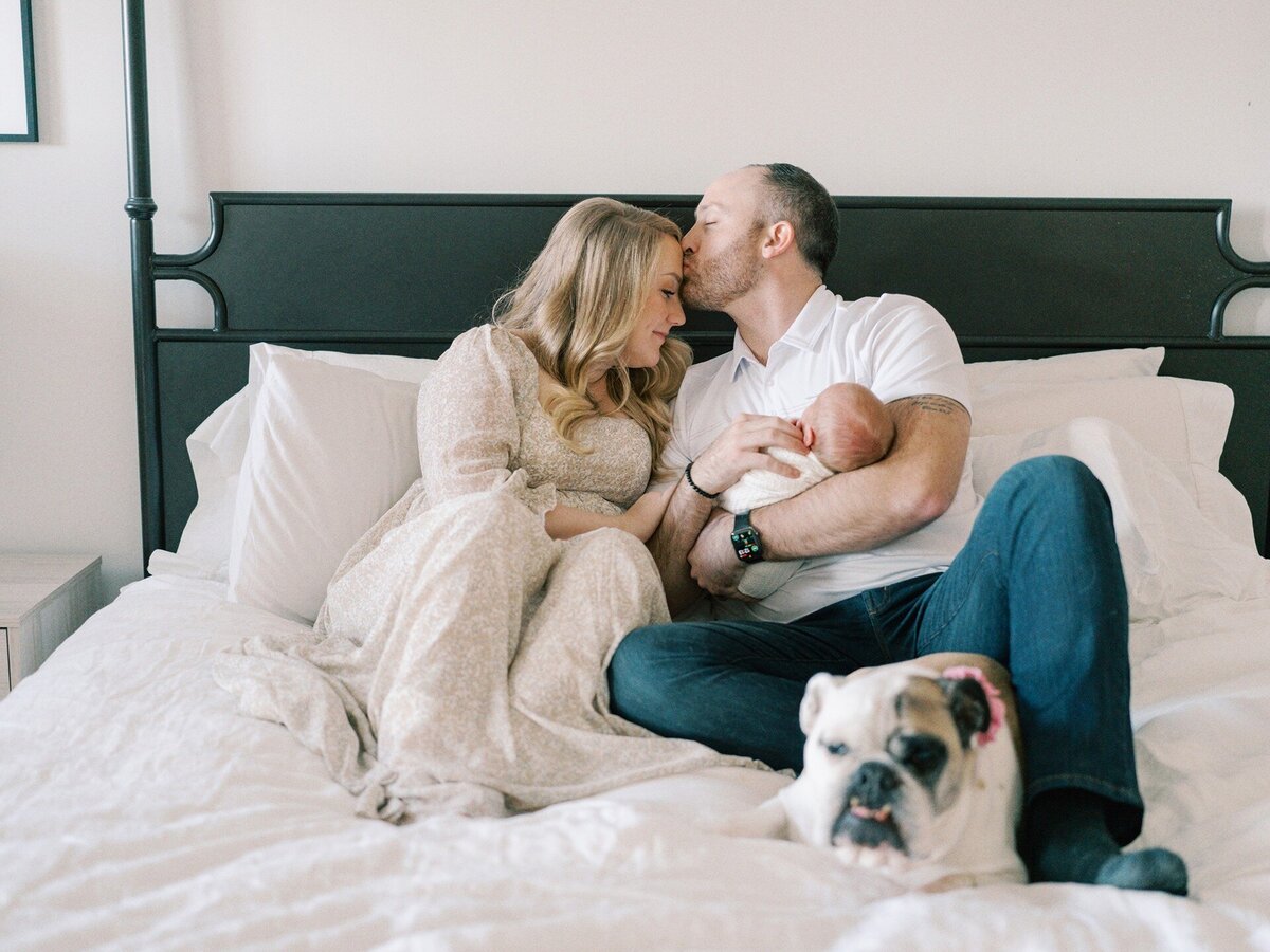 dad-holding-newborn-in-bed-with-bulldog