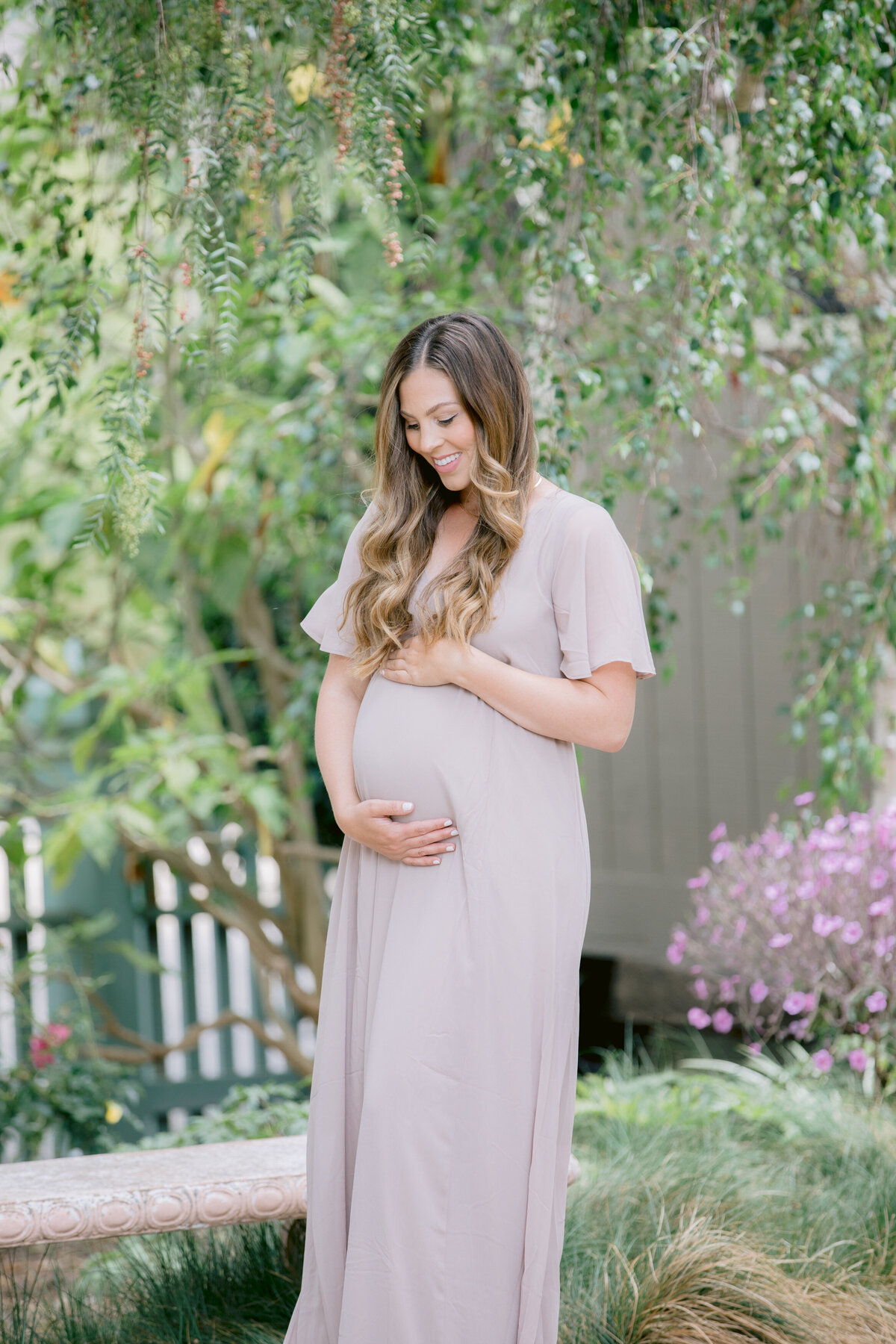 A pregnant woman holding her stomach and smiling