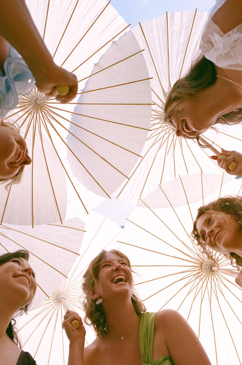 Woman hold garden umbrellas above their heads and smile at an outdoor wedding in Oregon.