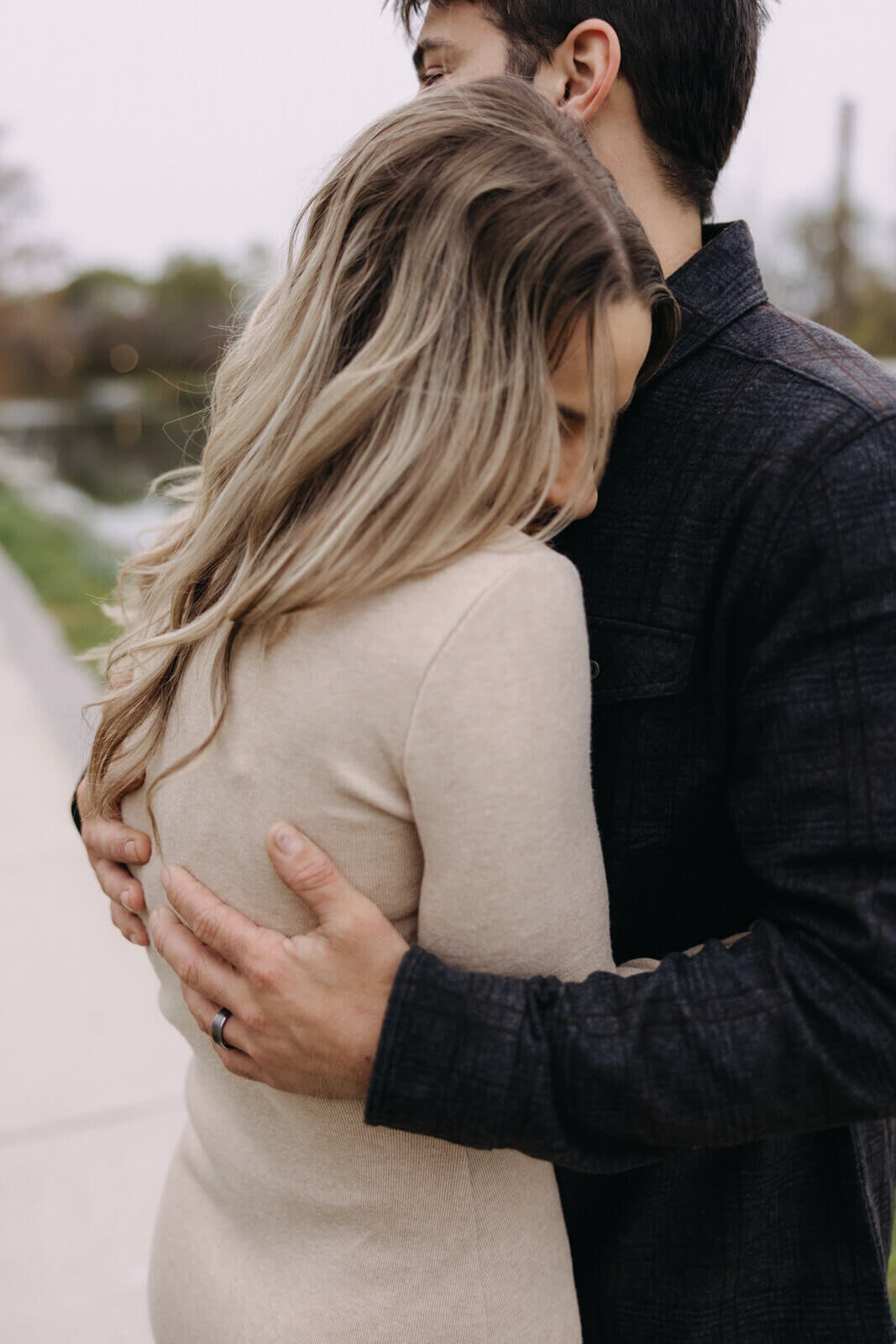 man and woman hugging standing by the lake at Finger Lakes maternity session