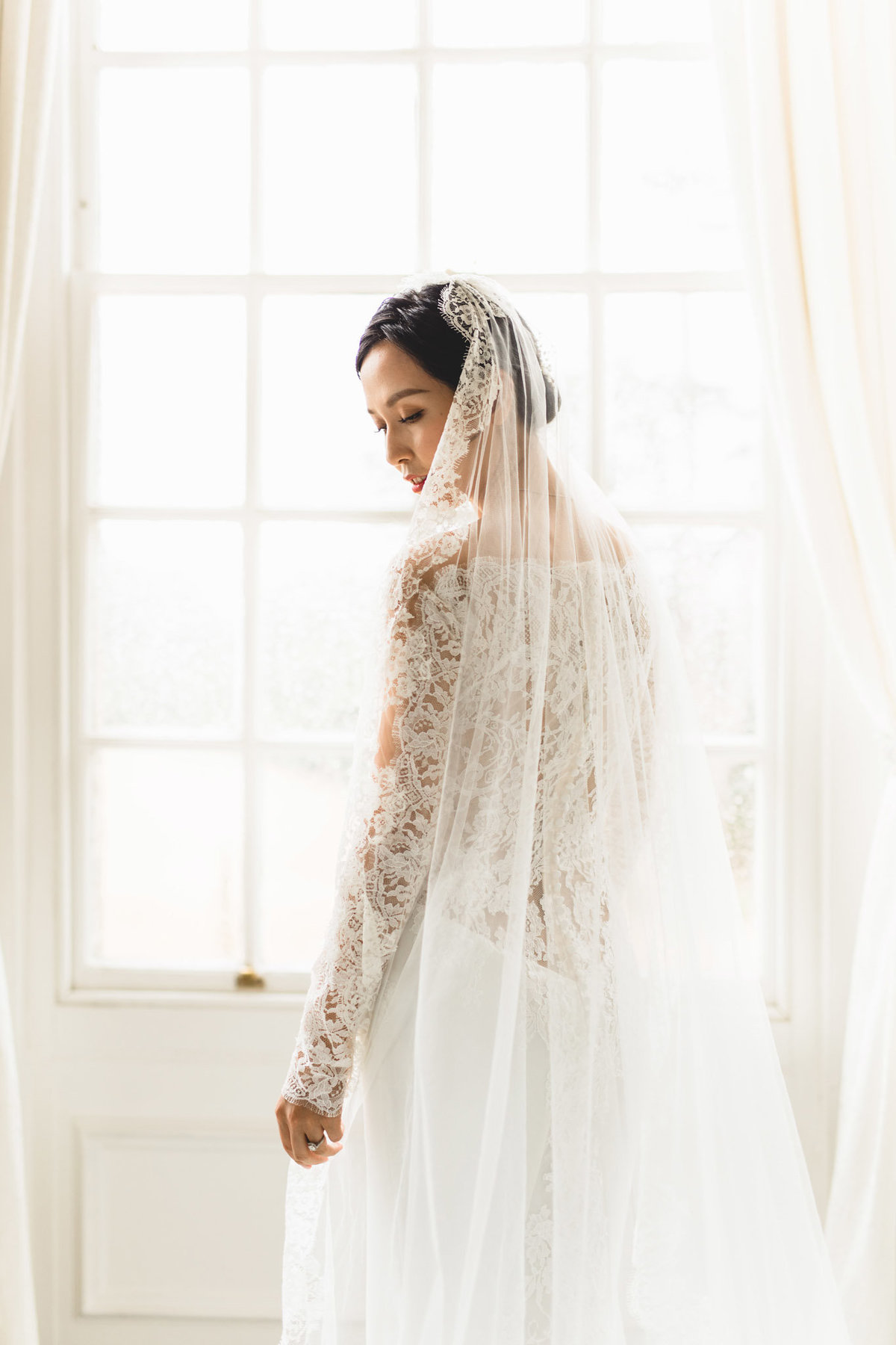 bride in a Vera Wang dress in front of her window in the bridal suite a Claridges