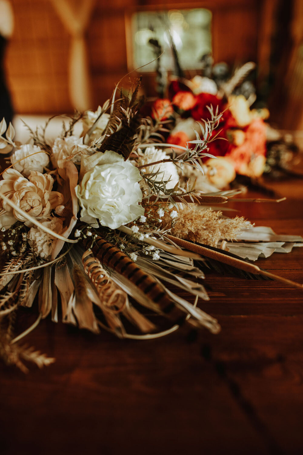 Rustic bouquet with feathers, roses, and dried foliage