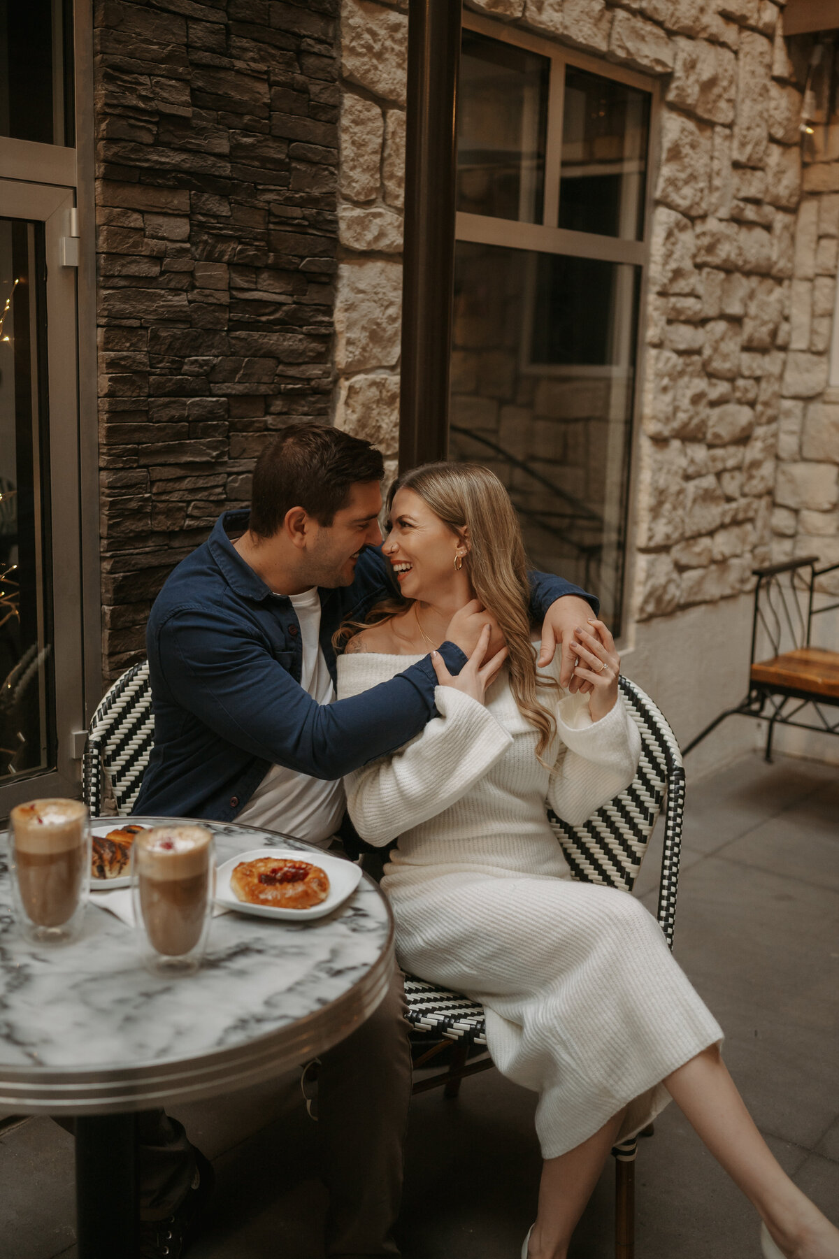 Photo of couple sitting outside laughing at coffee shop