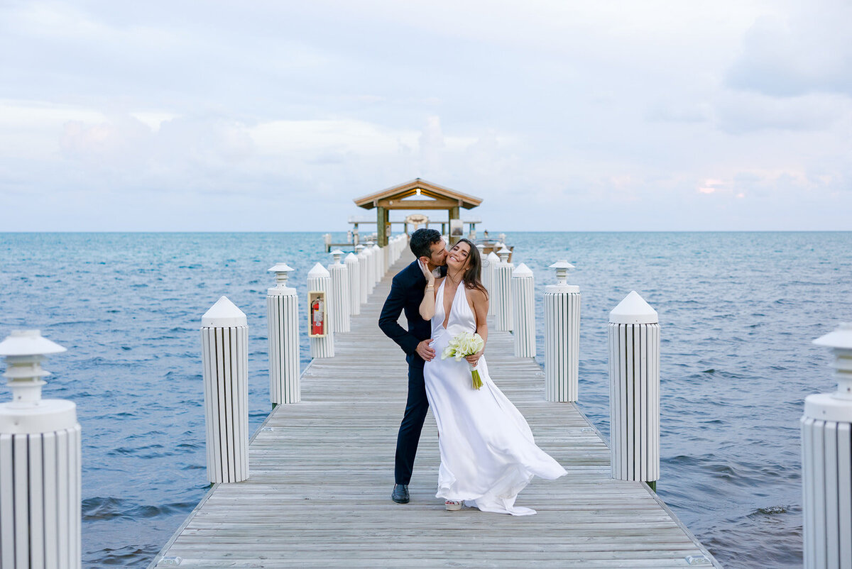 Minette and Evan share a tender kiss with the sky painted in soft hues at Casitas at Cheeca. Destination wedding photography by Claudia Amalia.
