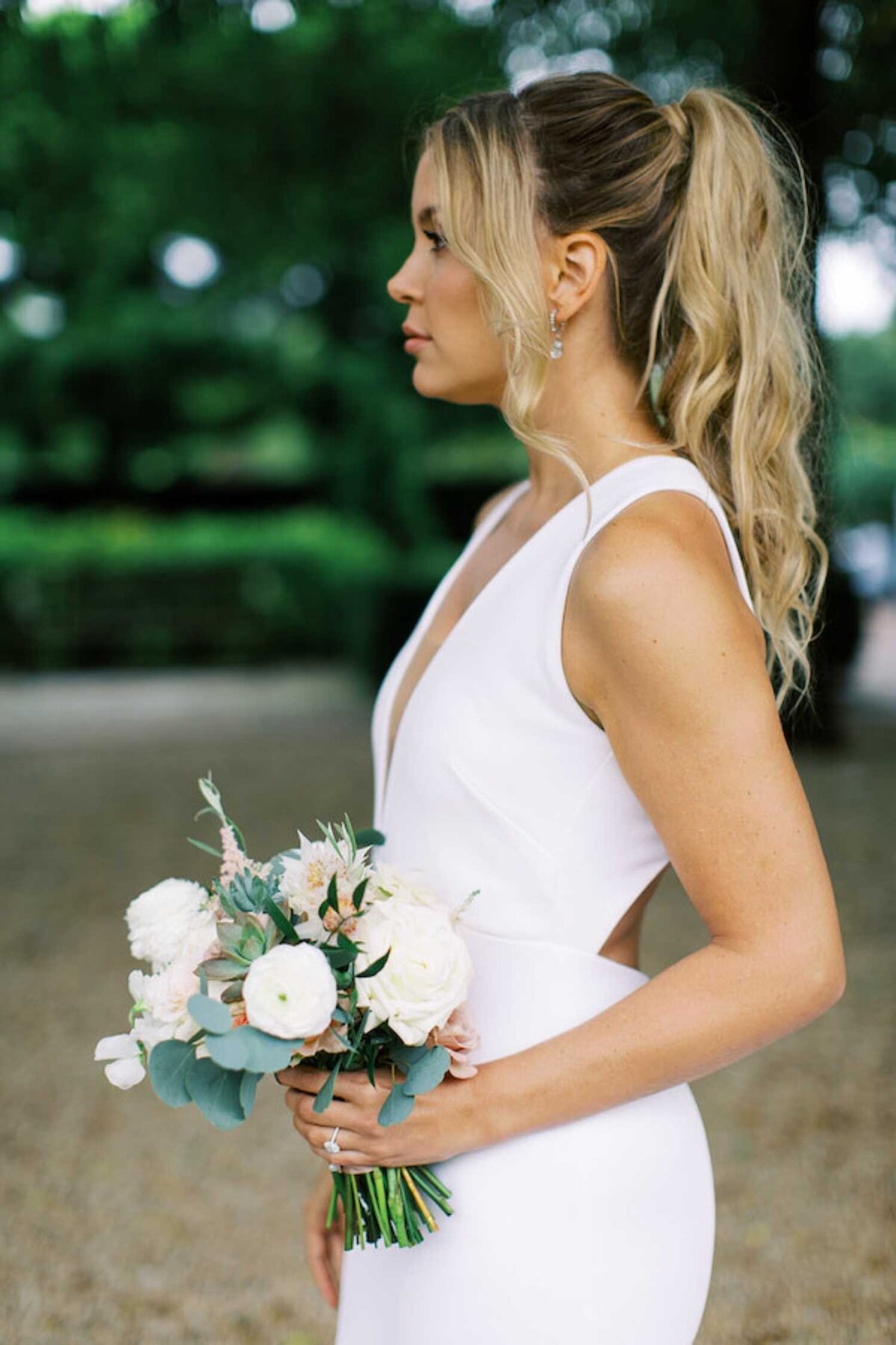 Sleek and modern cutout bridal gown with a ponytail hair style at a  luxury Chicago outdoor garden wedding.