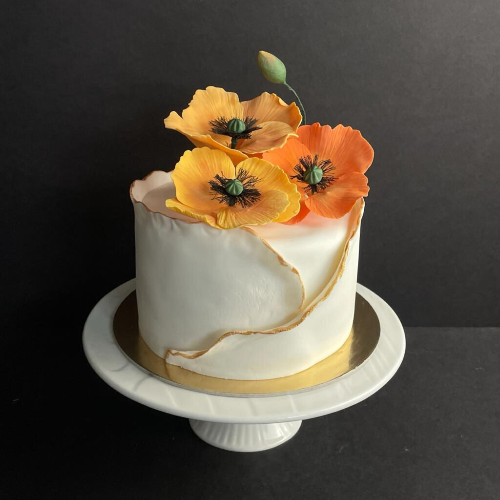 Fun spring-inspired white textured wedding cake surrounded with orange and yellow sugar flowers, created by Chartier YYC, elegant cakes & desserts in Calgary, AB, featured on the Brontë Bride Vendor Guide.
