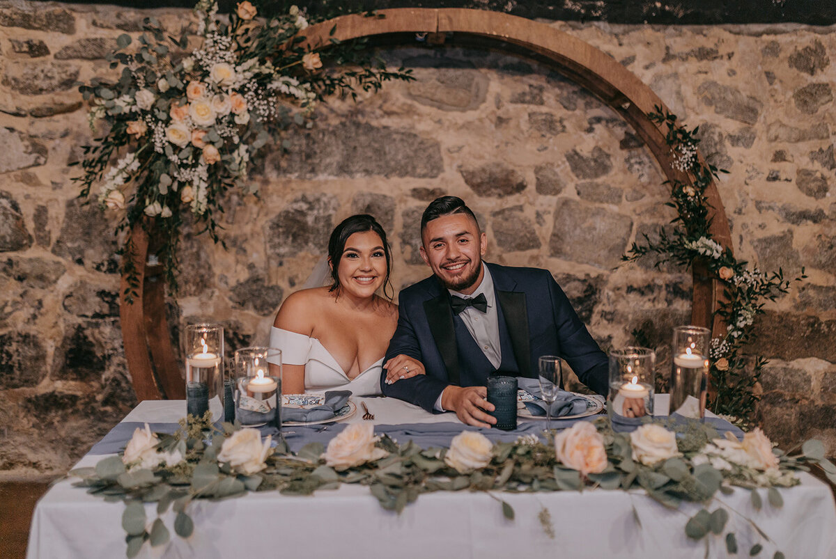Bride and groom portrait with floral arch designed with colorful flowers