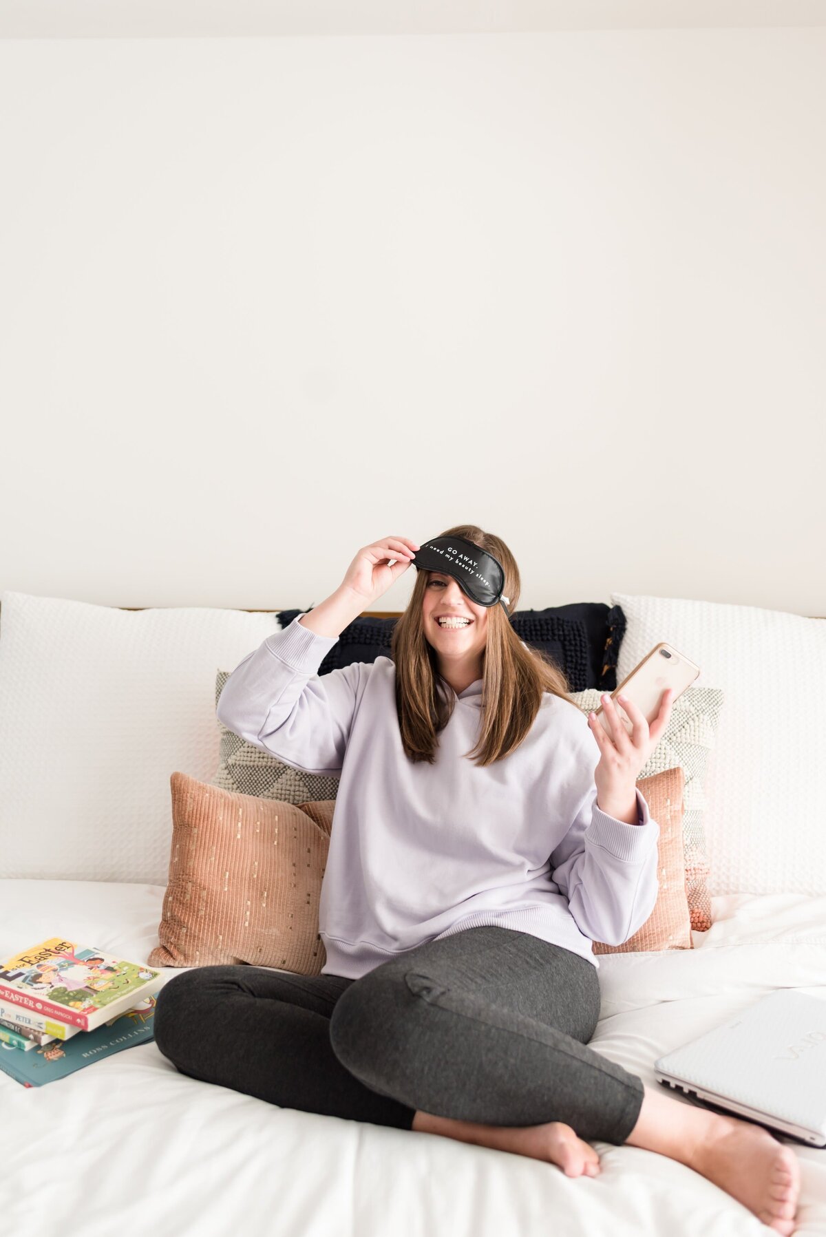 Fun photo of a Nashville business owner with an iphone in one hand and her other hand pulling up a sleeping mask from her eyes