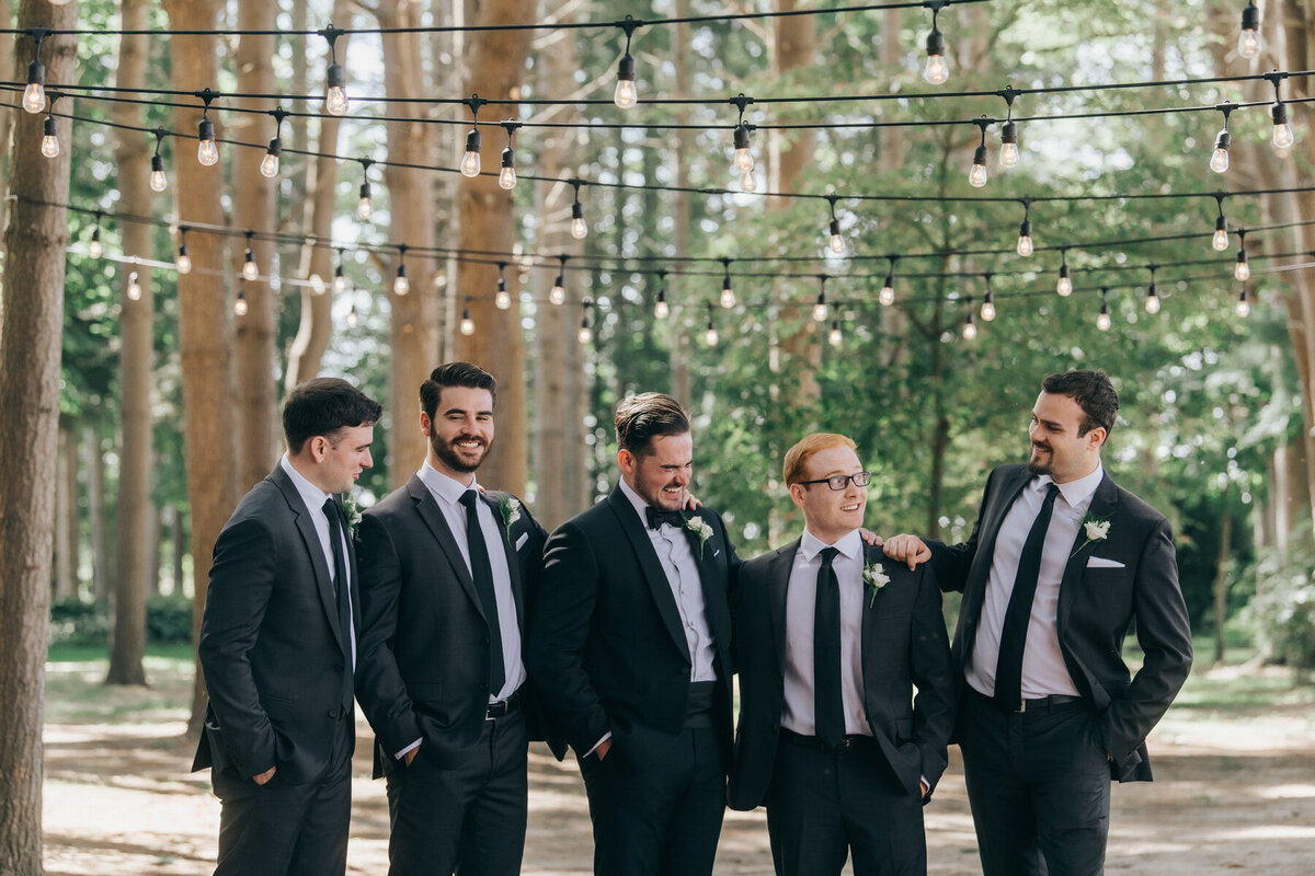 Groomsmen posing for photos with the groom in black tie attire on a Summer wedding day at Wheatfield Estate