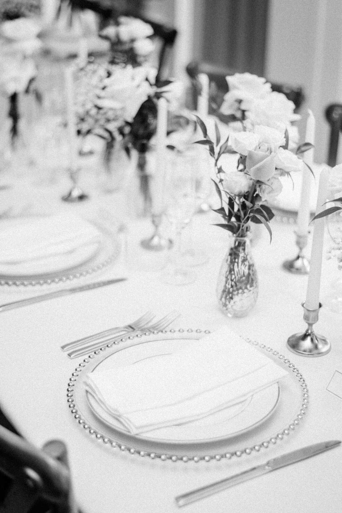 A classic black-and-white photograph of an elegantly set dining table with floral arrangements, seen through the large, bright windows of a sophisticated Oakville home