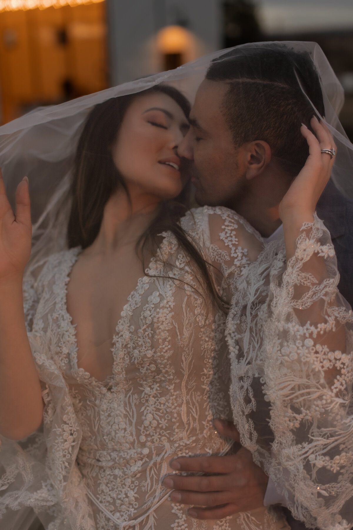 A couple share an intimate kiss with a veil covering them.