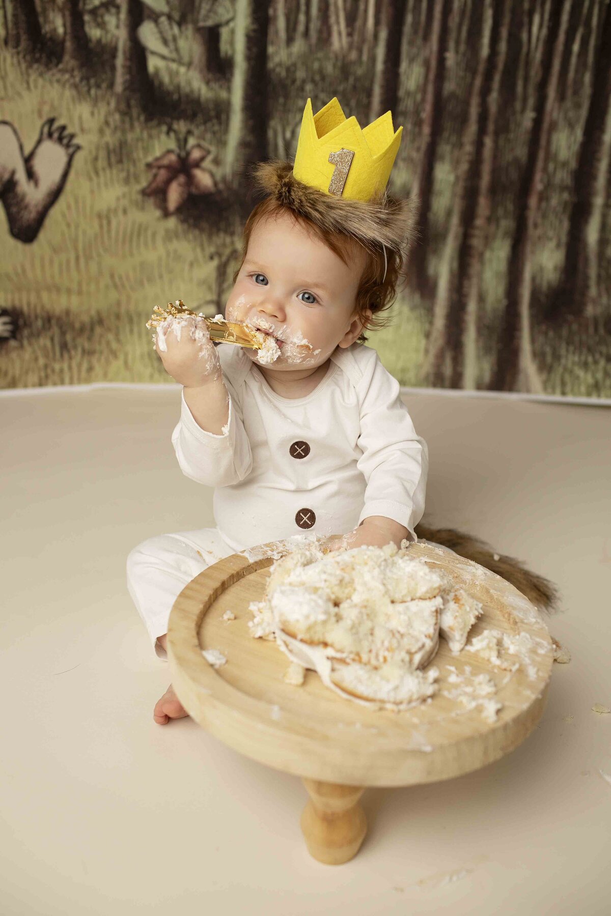 Smiling redhead birthday boy covered in cake frosting, enjoying his Where the Wild Things Are themed cake smash