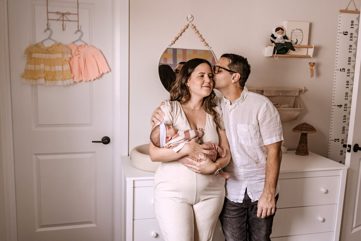 mom and dad with baby in nursery