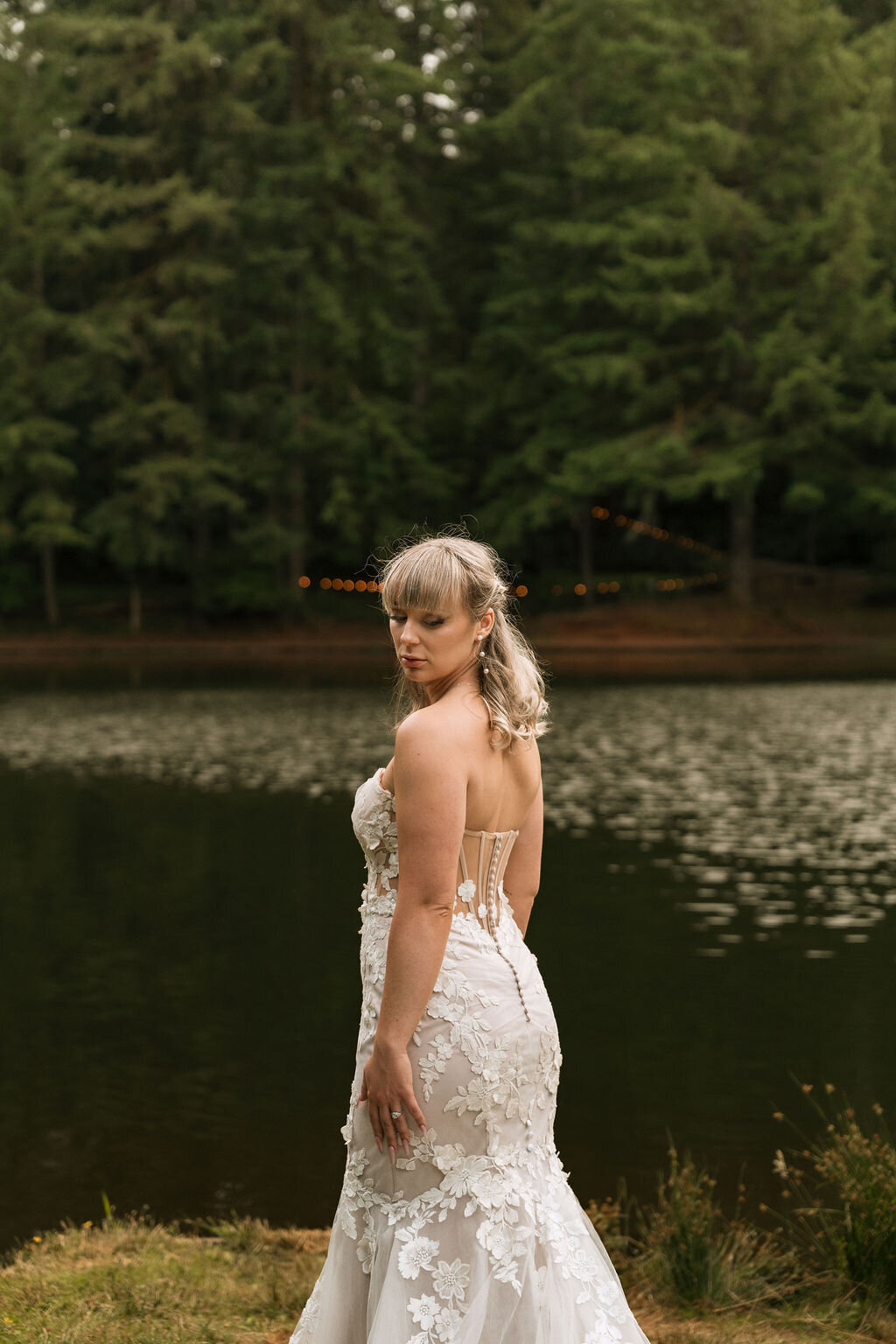 A bride standing outdoors by water representing bridal makeup done by Looks with Libby.