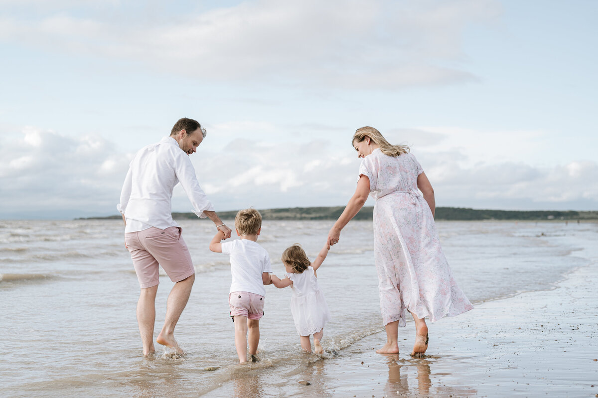 Beautiful family photography of a family walking hand-in-hand along a beach at sunset
