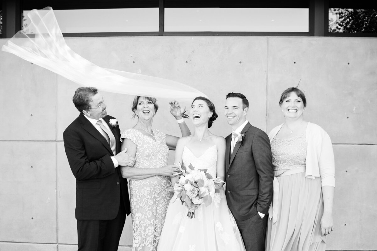 candid photo of bride and groom with family laughing during family portraits