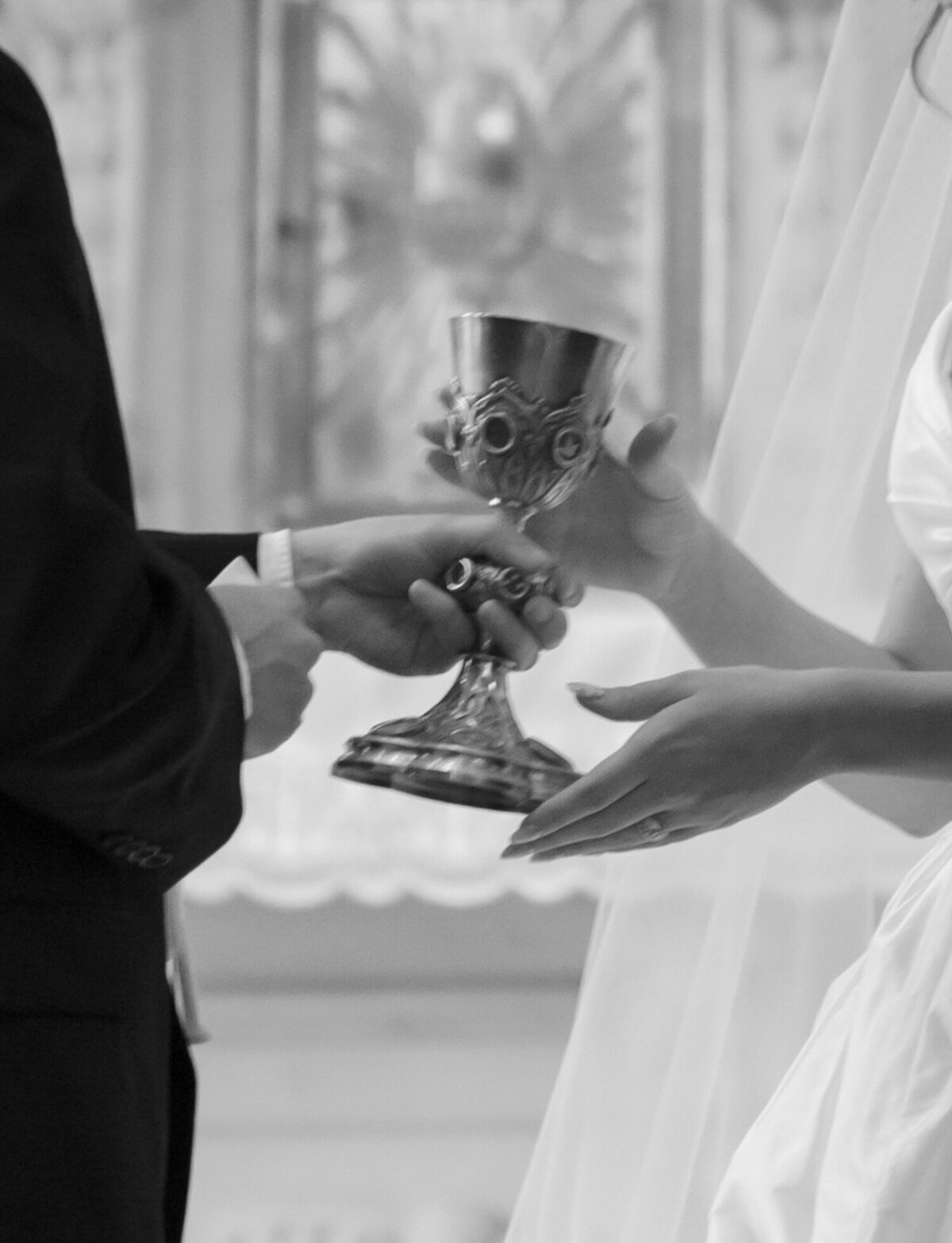 handoff of ornate communion cup during a catholic mass wedding at St. Peter and Paul in Detroit
