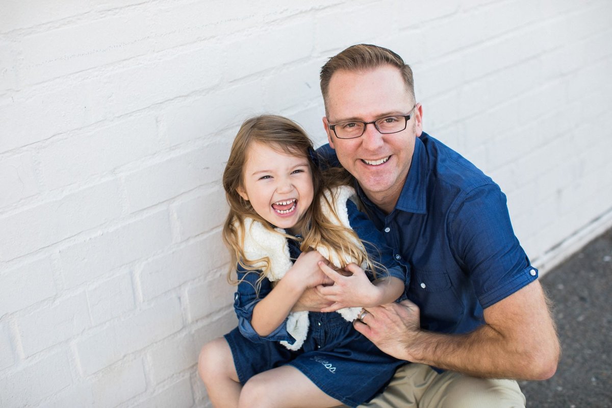 Little girl laughs as her daddy tickles her during a photo shoot