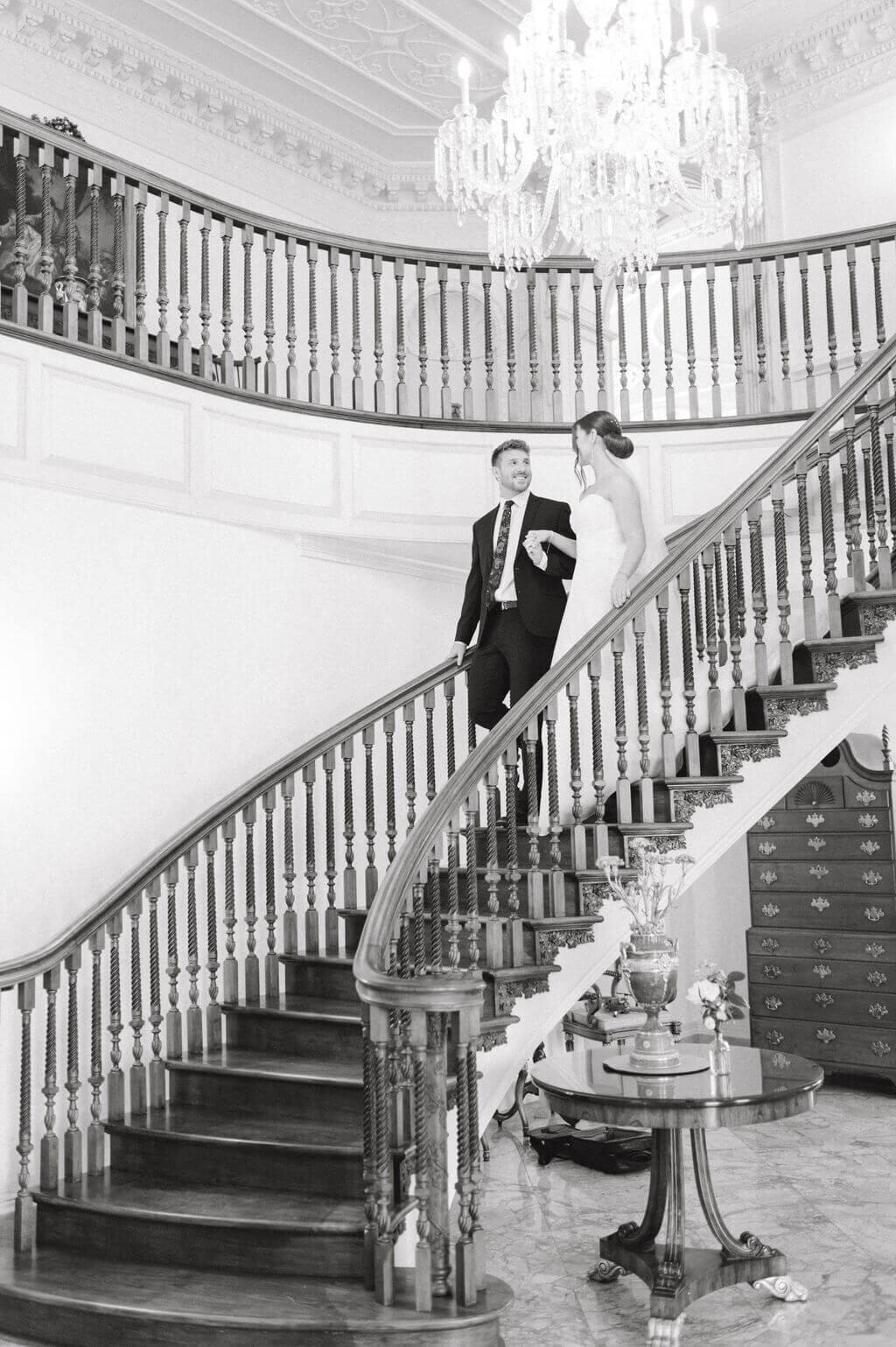 Wedding photo of bride and groom walking down grand staircase at the Estate at River Run