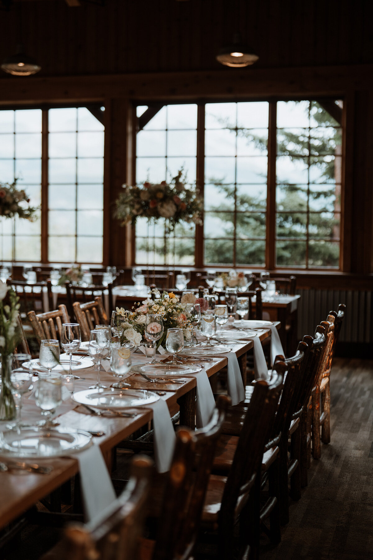 Long dining tables with floral centerpieces set for elegant Ten Mile Station mountain wedding reception.